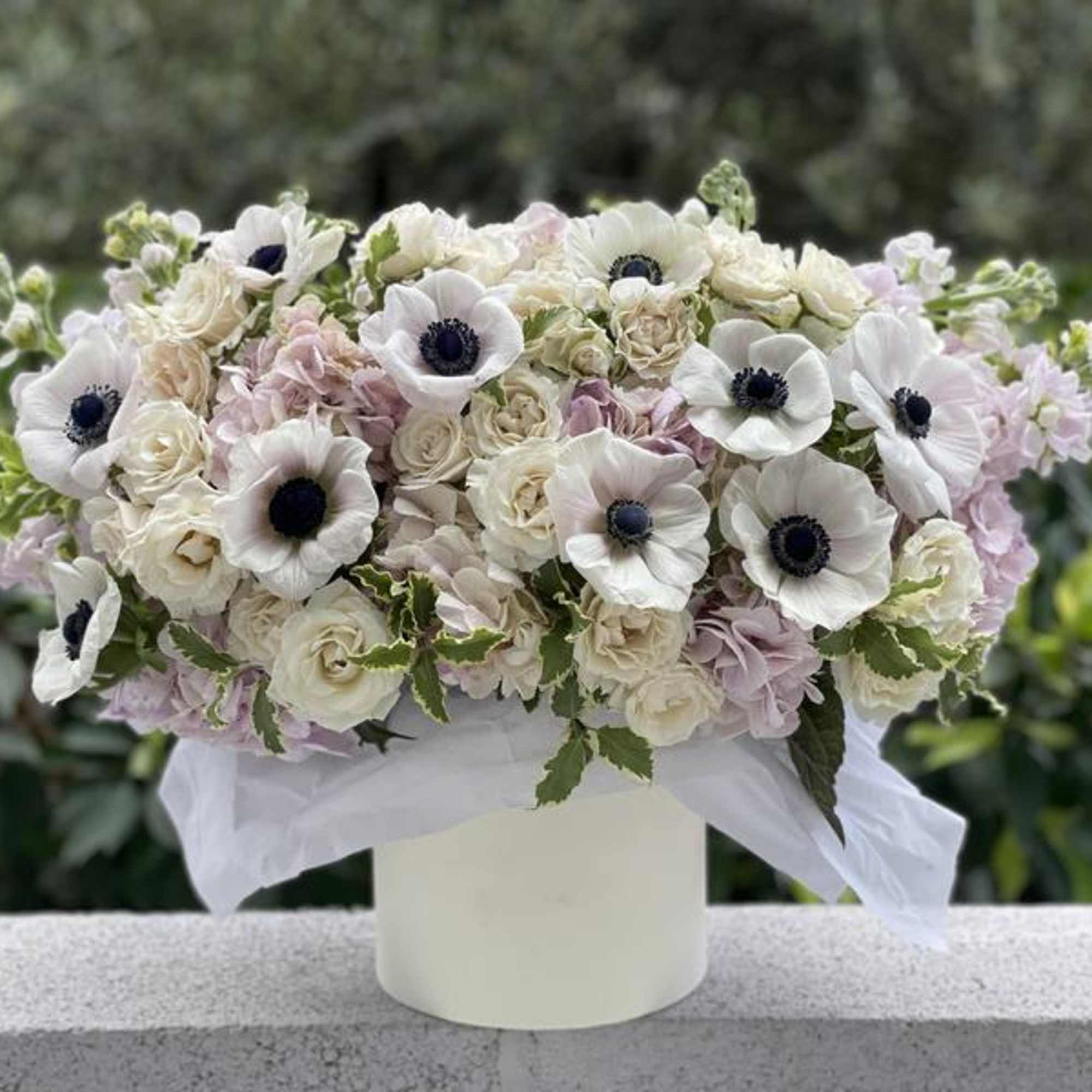 White and blush floral arrangement in a white vase