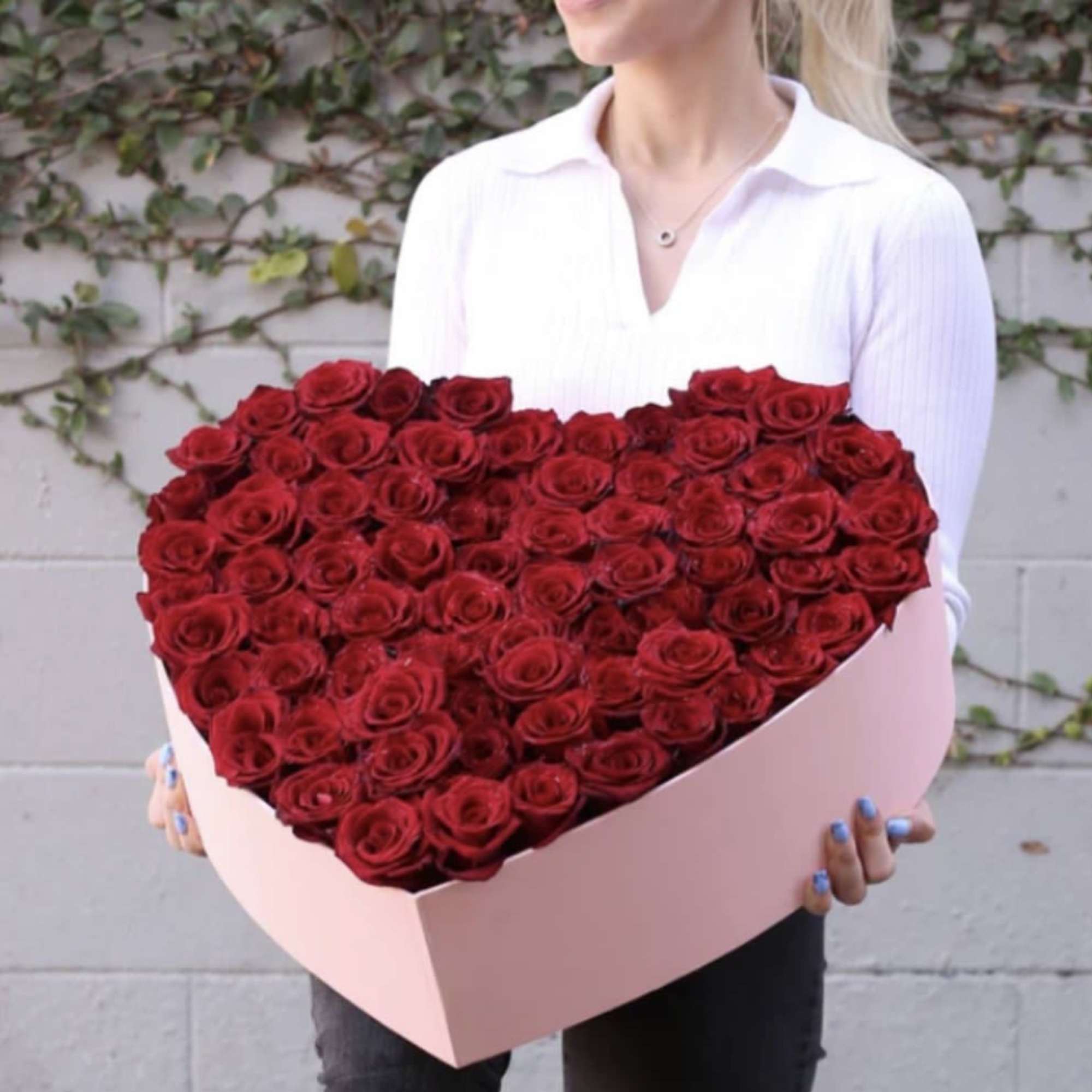 Heart-shaped box filled with red roses held by a person