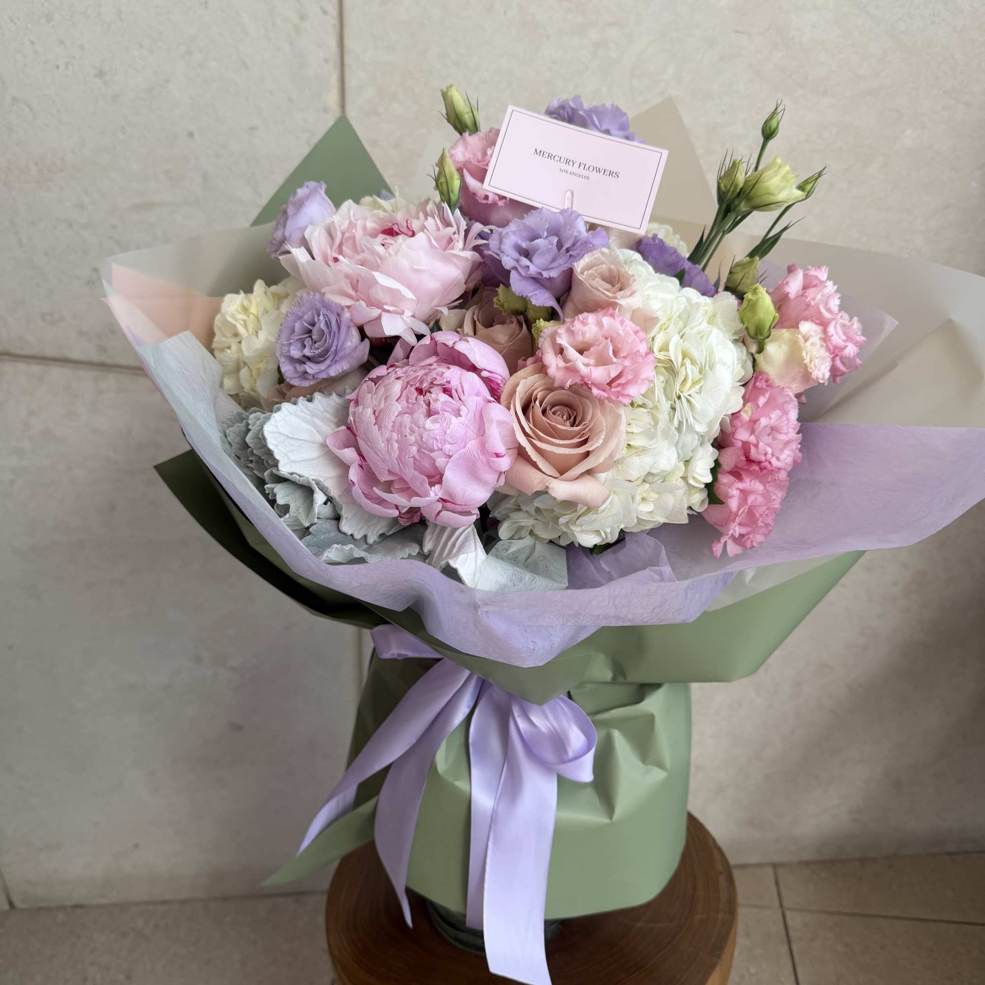 Pastel bouquet of pink, lavender, and white flowers wrapped in green paper, photo 5 of 8