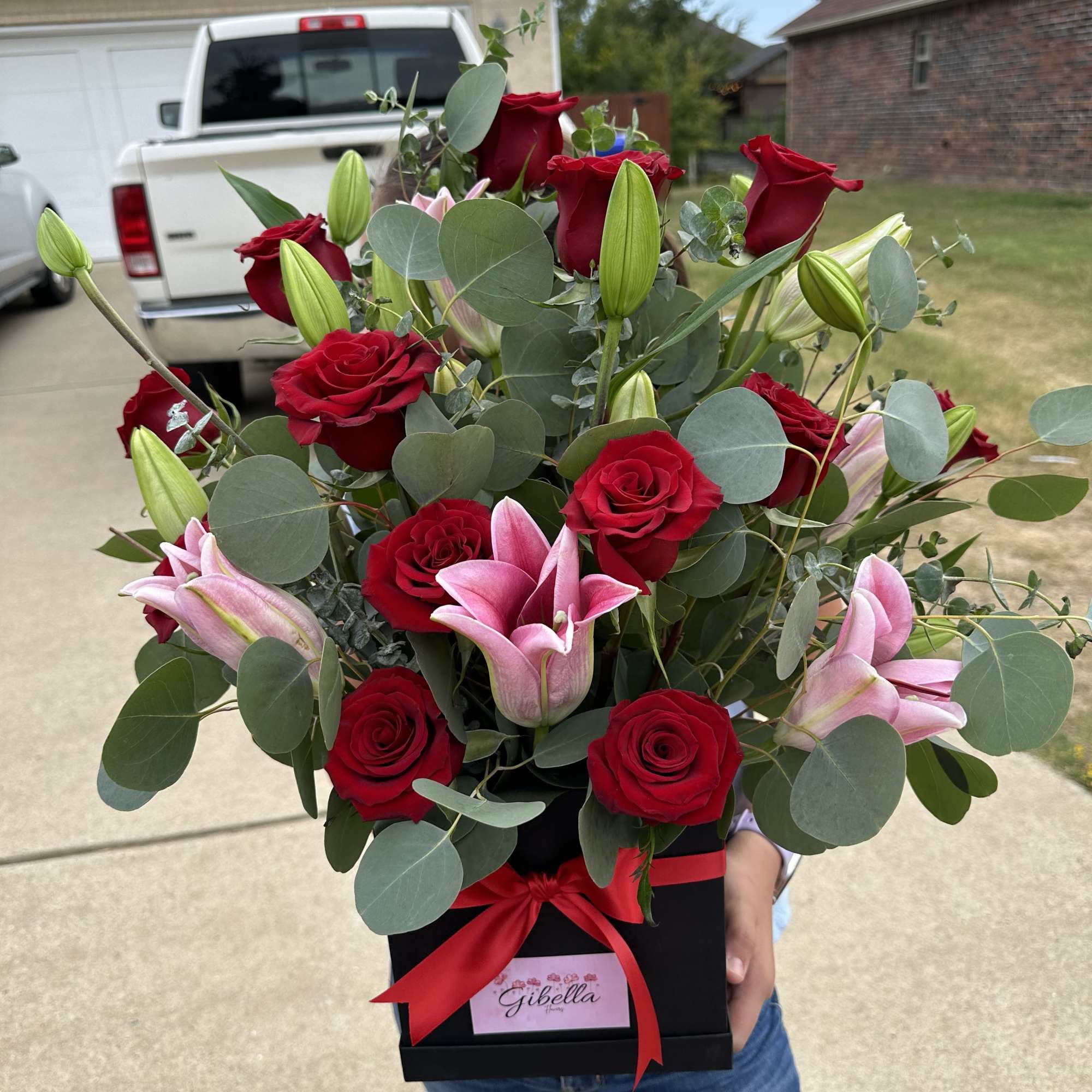 Red roses and pink lilies in a black gift box with a red ribbon