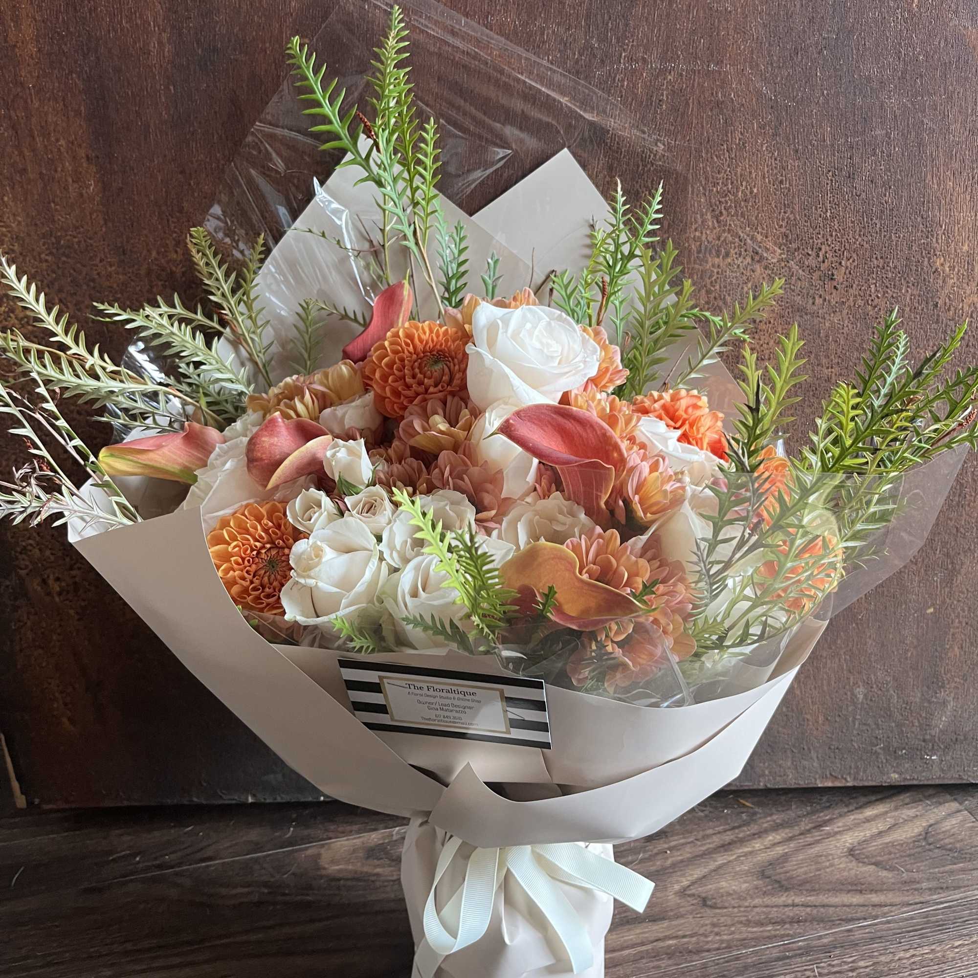 Bouquet of orange and white flowers wrapped in white paper with a ribbon