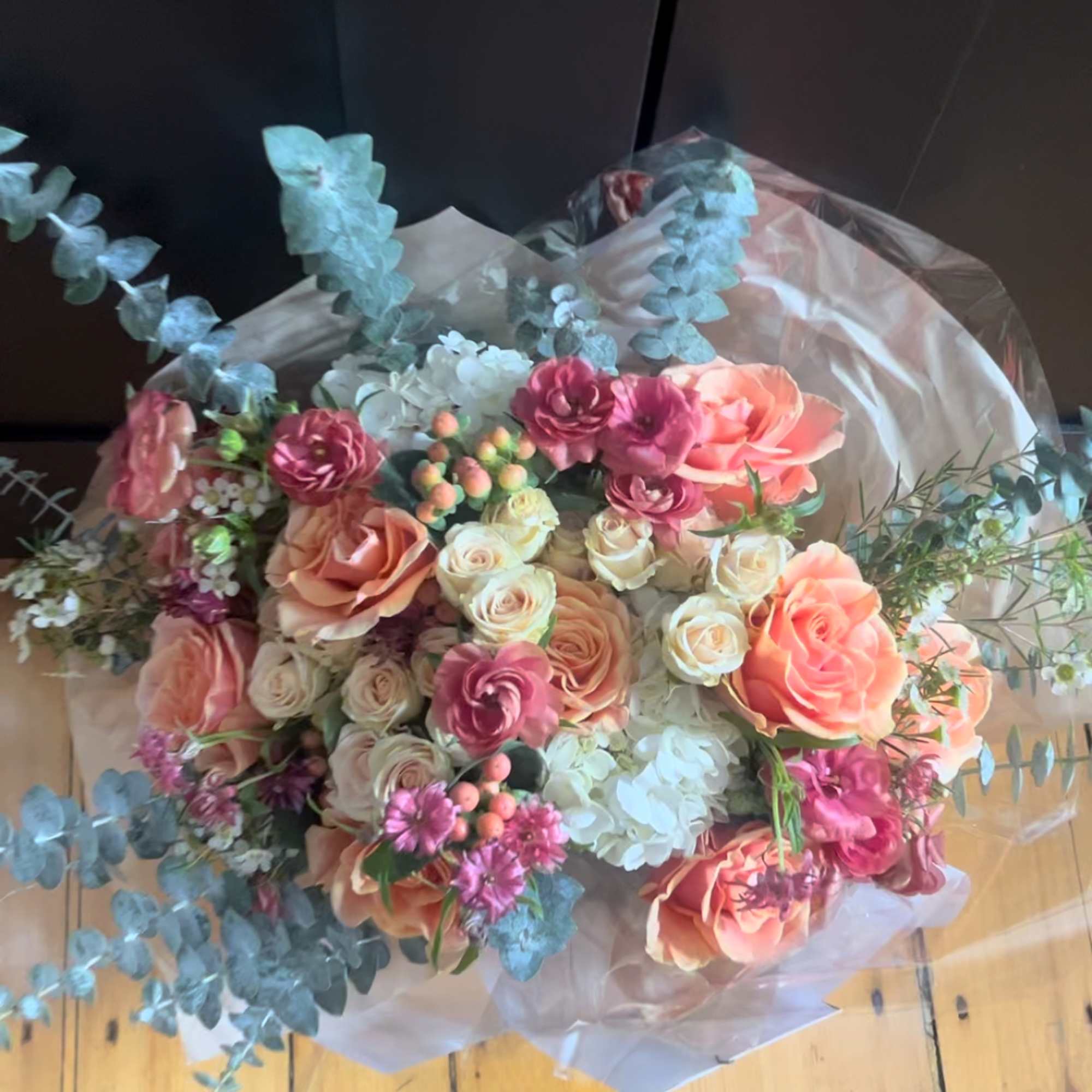 Bouquet of peach and pink roses with white blooms and eucalyptus
