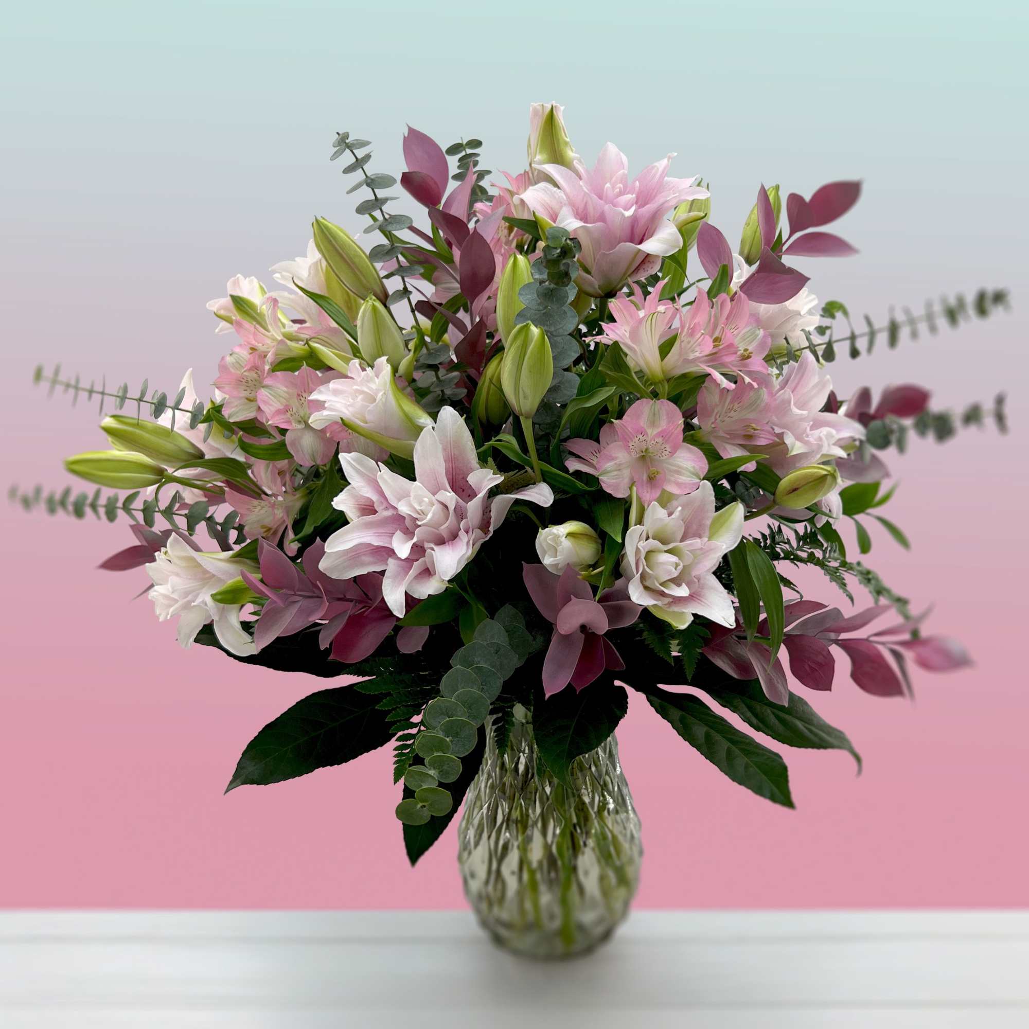 Pink and white lily bouquet in a clear glass vase