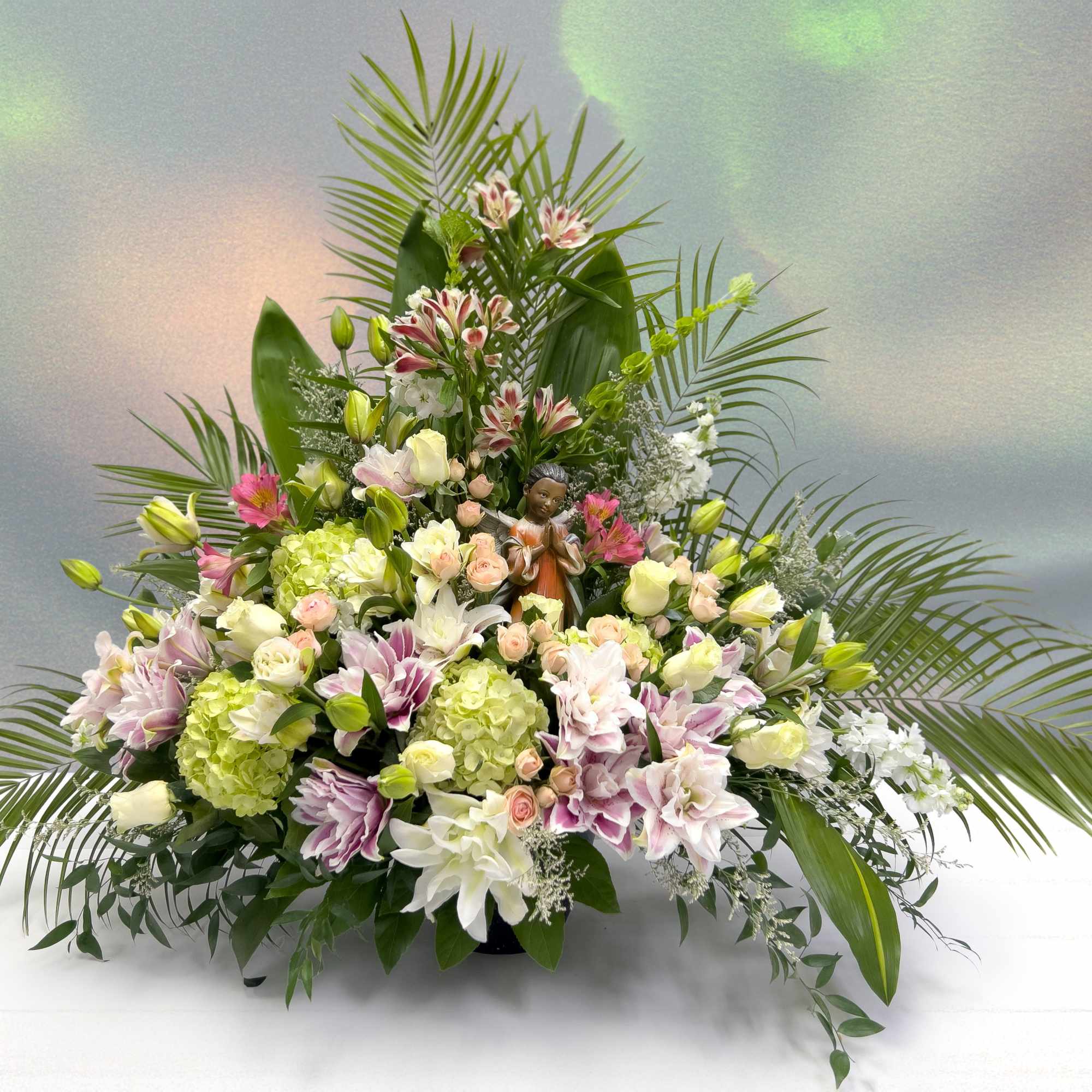 Large floral arrangement with lilies, roses, and green hydrangeas