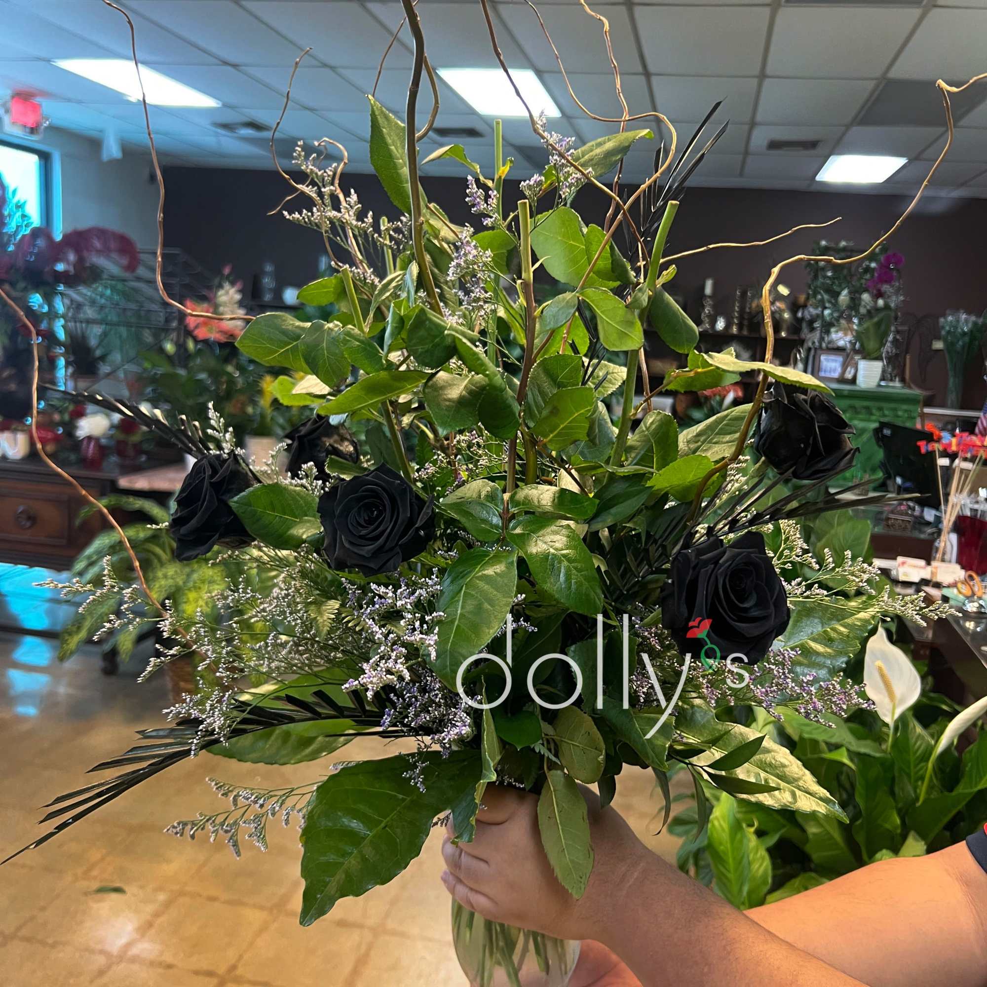 Tall bouquet of black roses and greenery in a glass vase