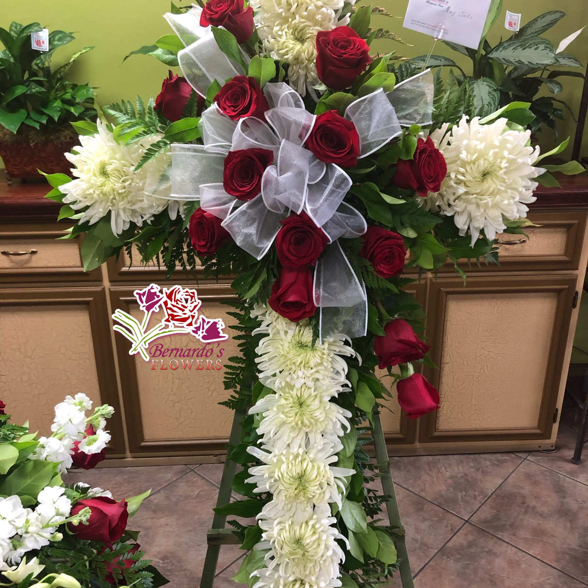 Standing floral cross with red roses and white chrysanthemums on an easel