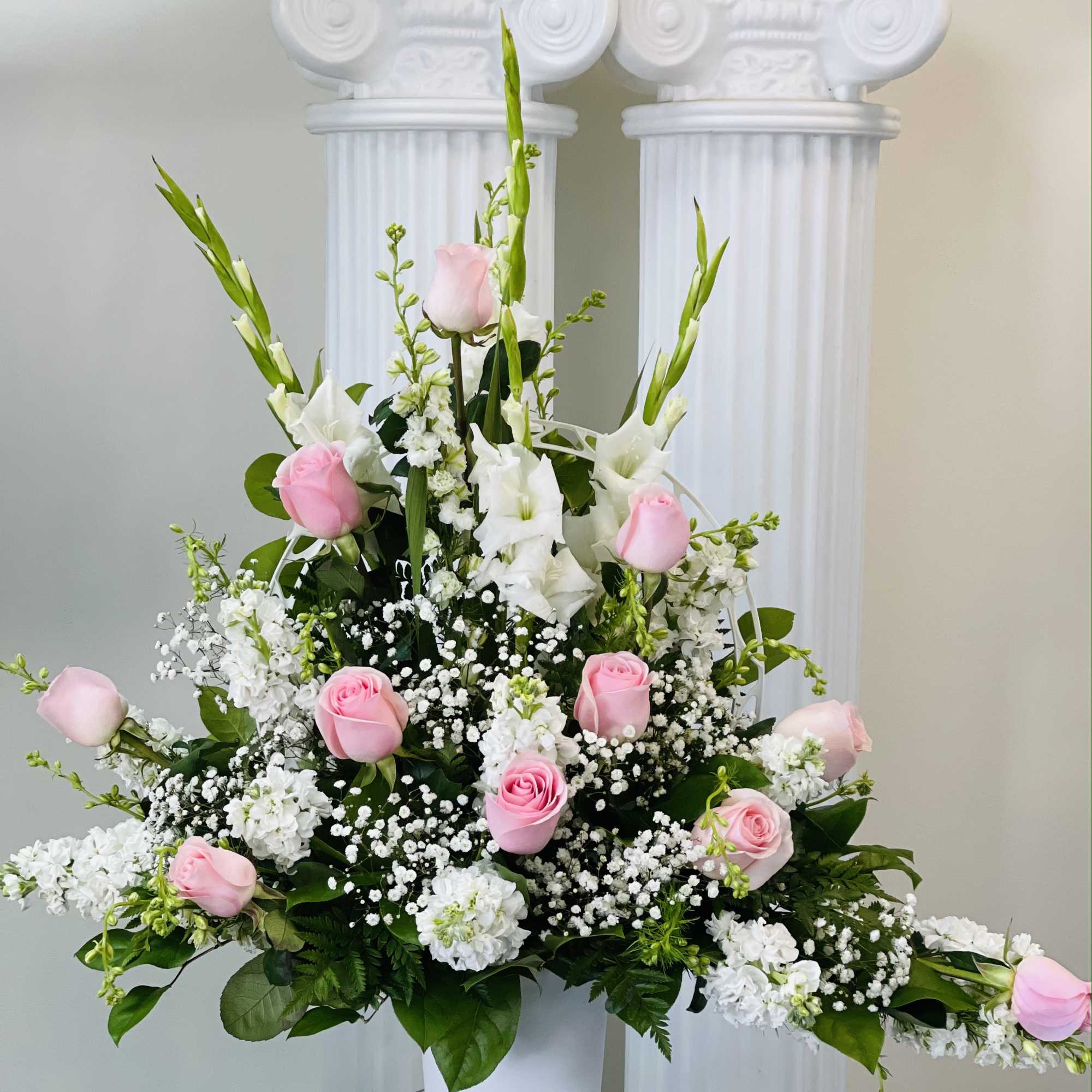 Pink roses and white gladiolus in a white vase arrangement