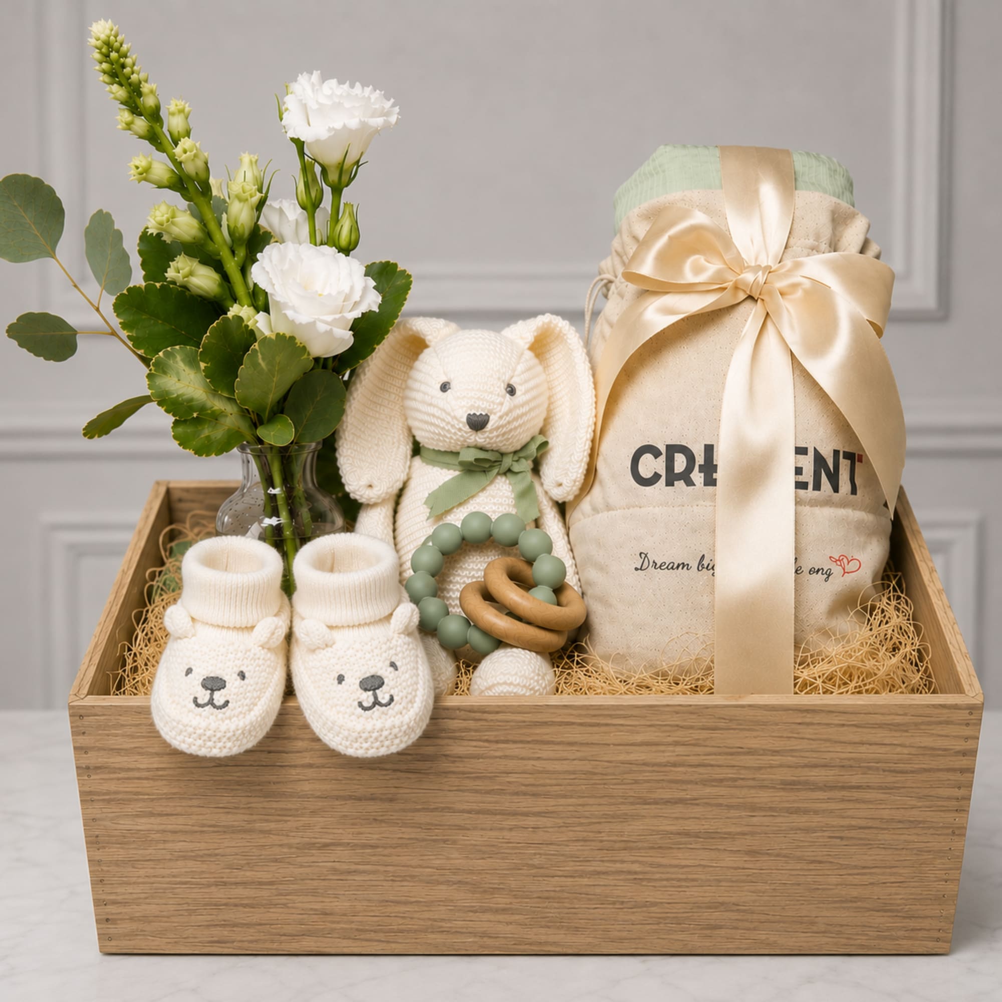 Gift basket with white flowers, a plush bunny, baby booties, and a wrapped item