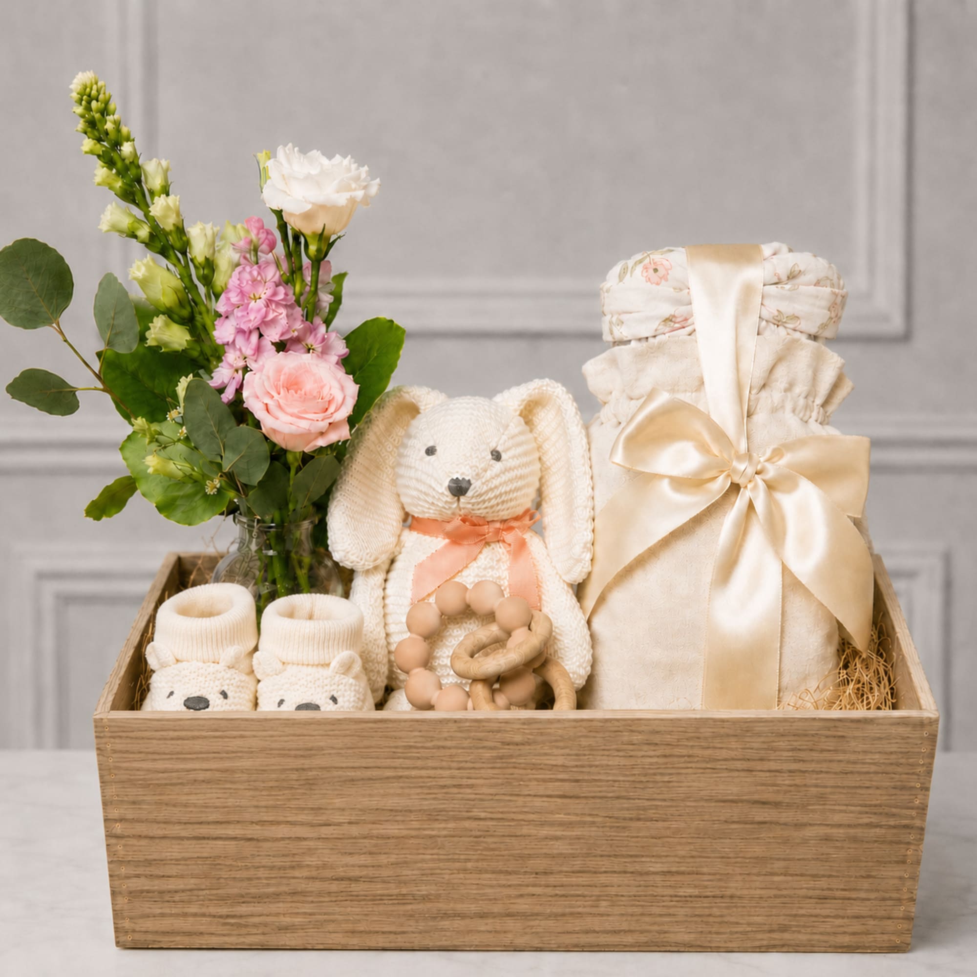 Gift basket with a small flower arrangement, baby clothes, and a plush bunny