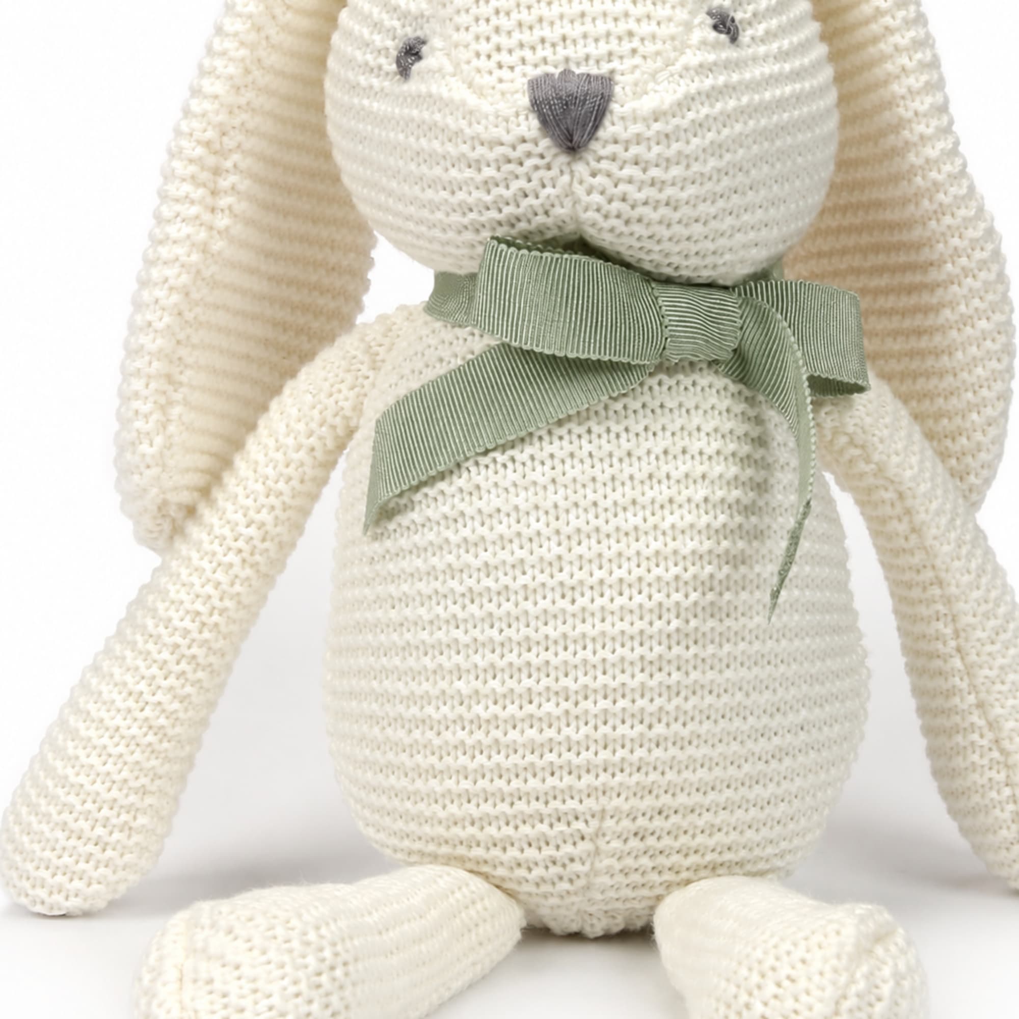 Cream knitted stuffed bunny with a green ribbon bow
