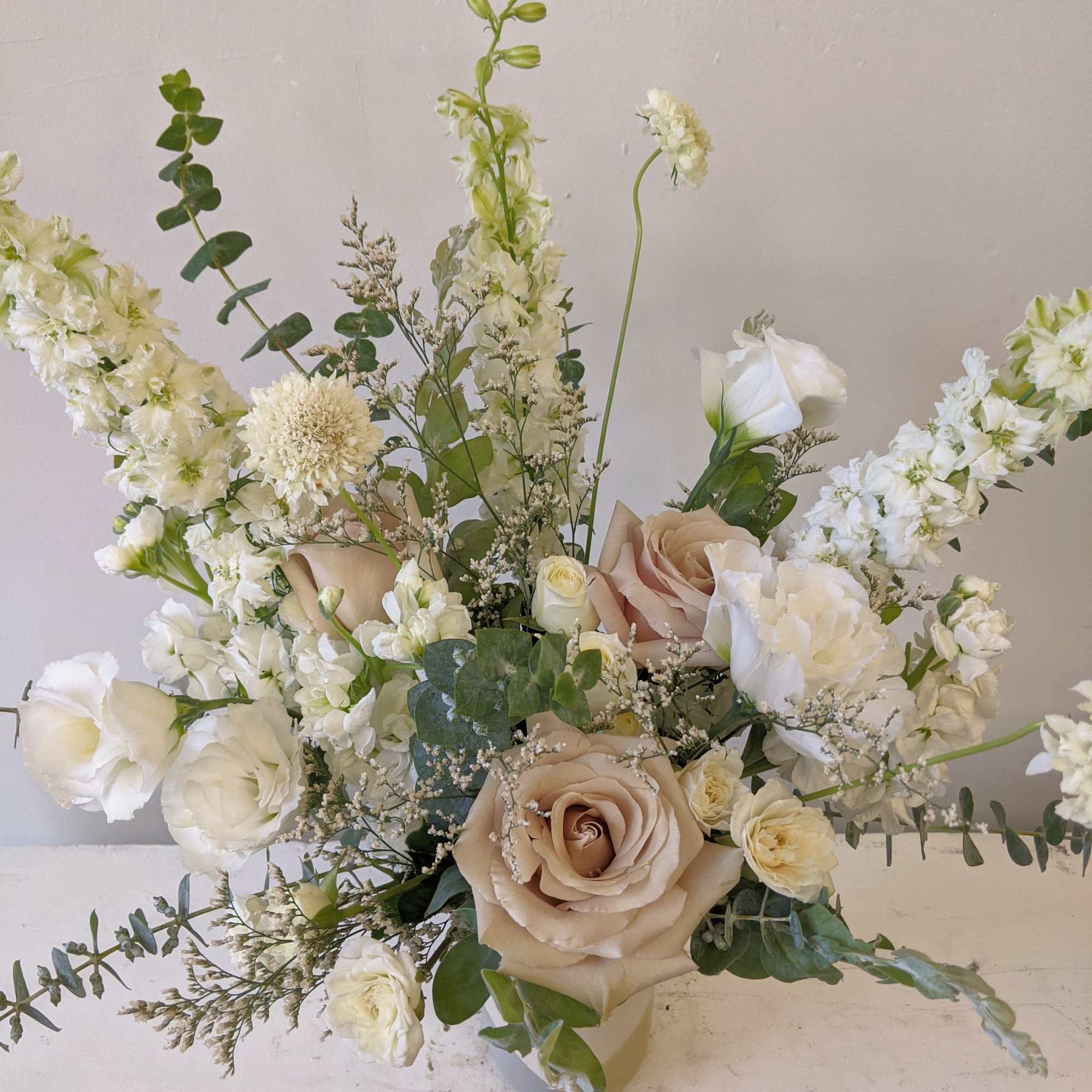 Cream and blush floral arrangement in a vase with tall white blooms