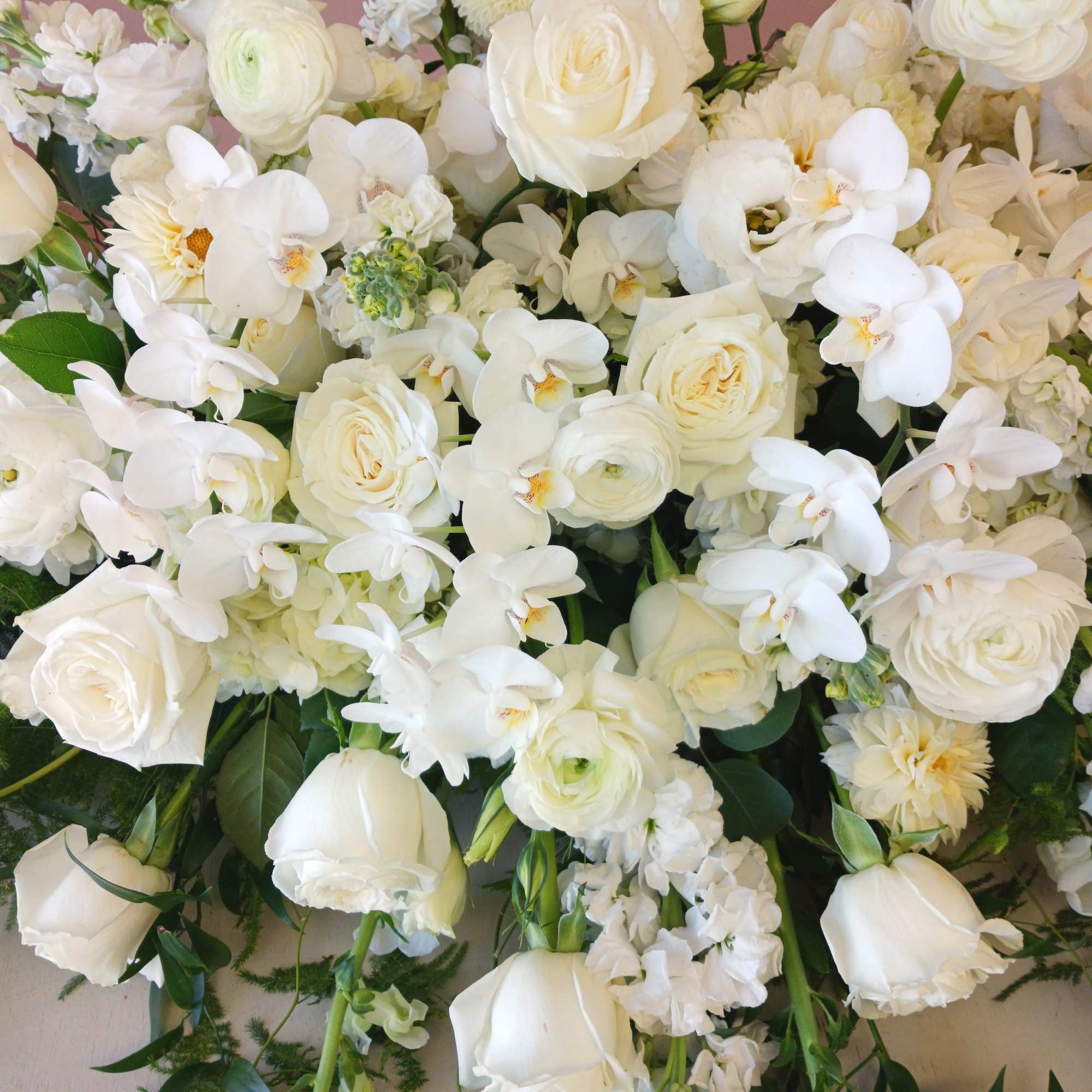 White roses and orchids arranged in a dense bouquet
