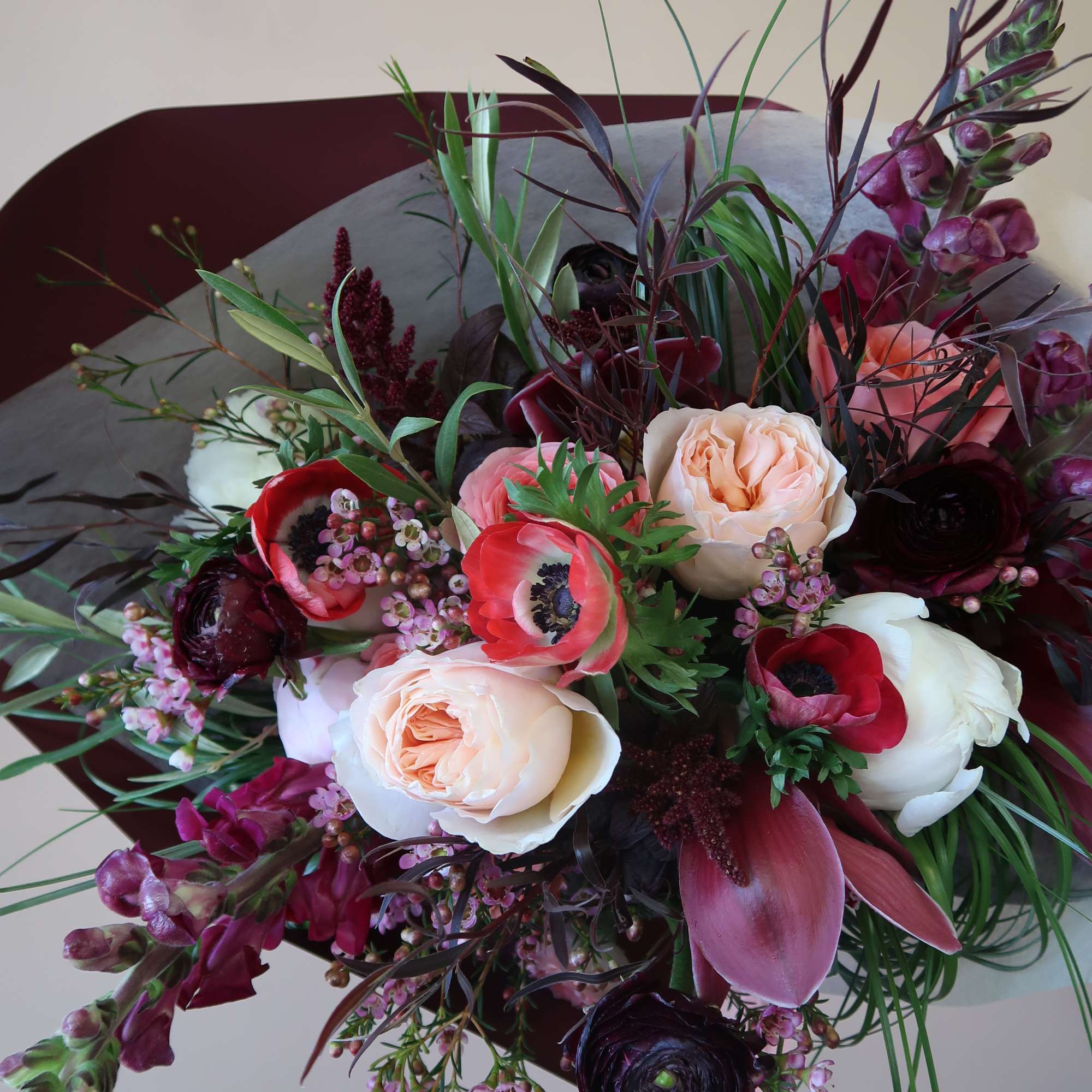 Bouquet of blush roses, red anemones, and burgundy blooms