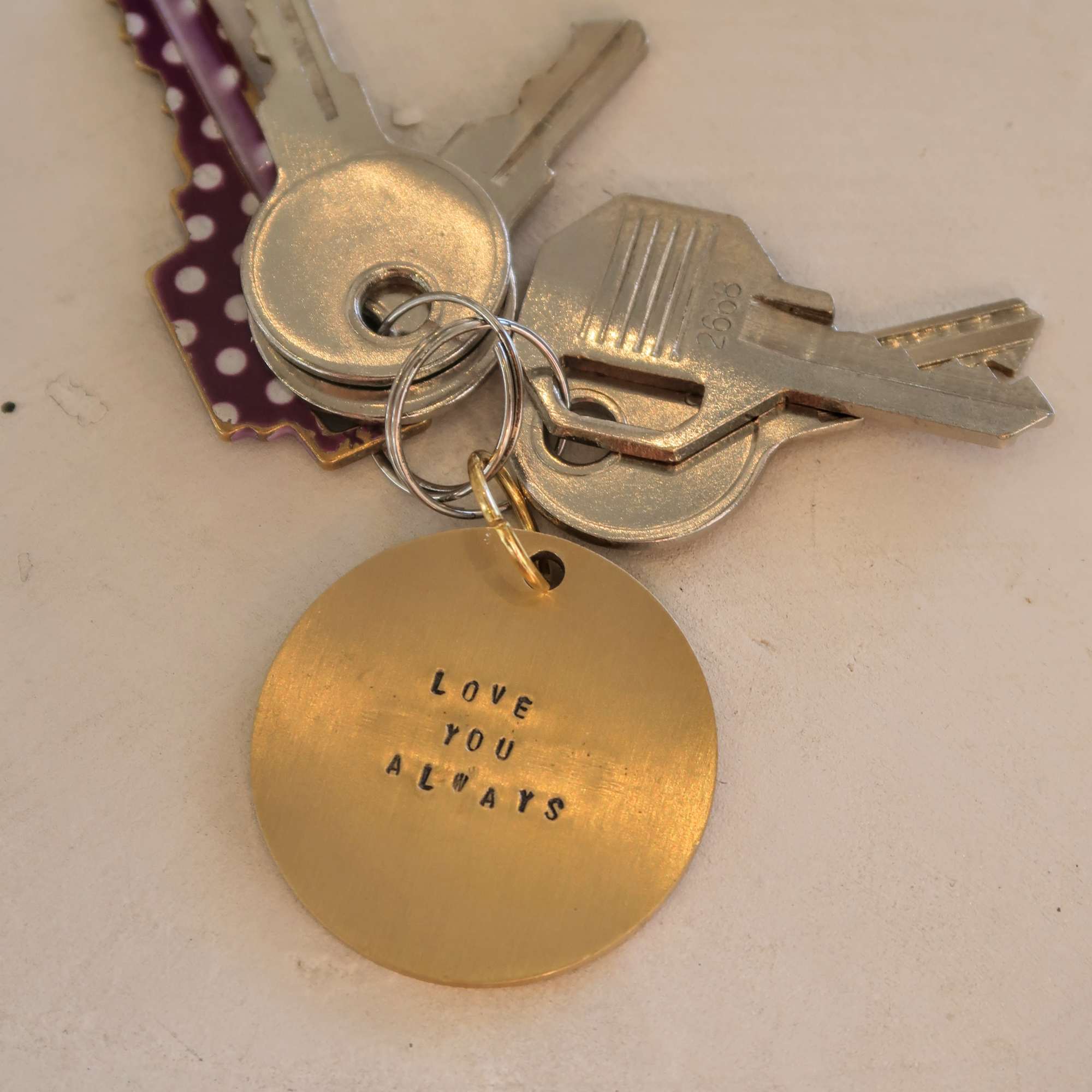 A keyring with several metal keys and a gold tag reading "LOVE YOU ALWAYS".