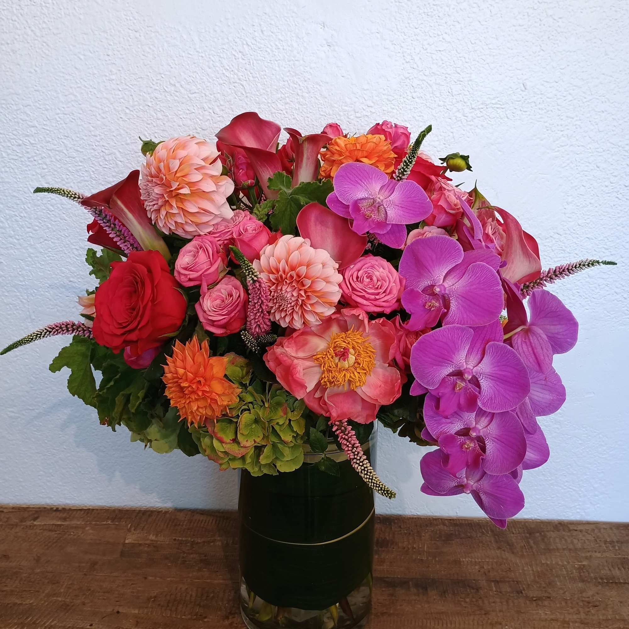 Mixed bouquet of pink, red, and orange flowers in a glass vase