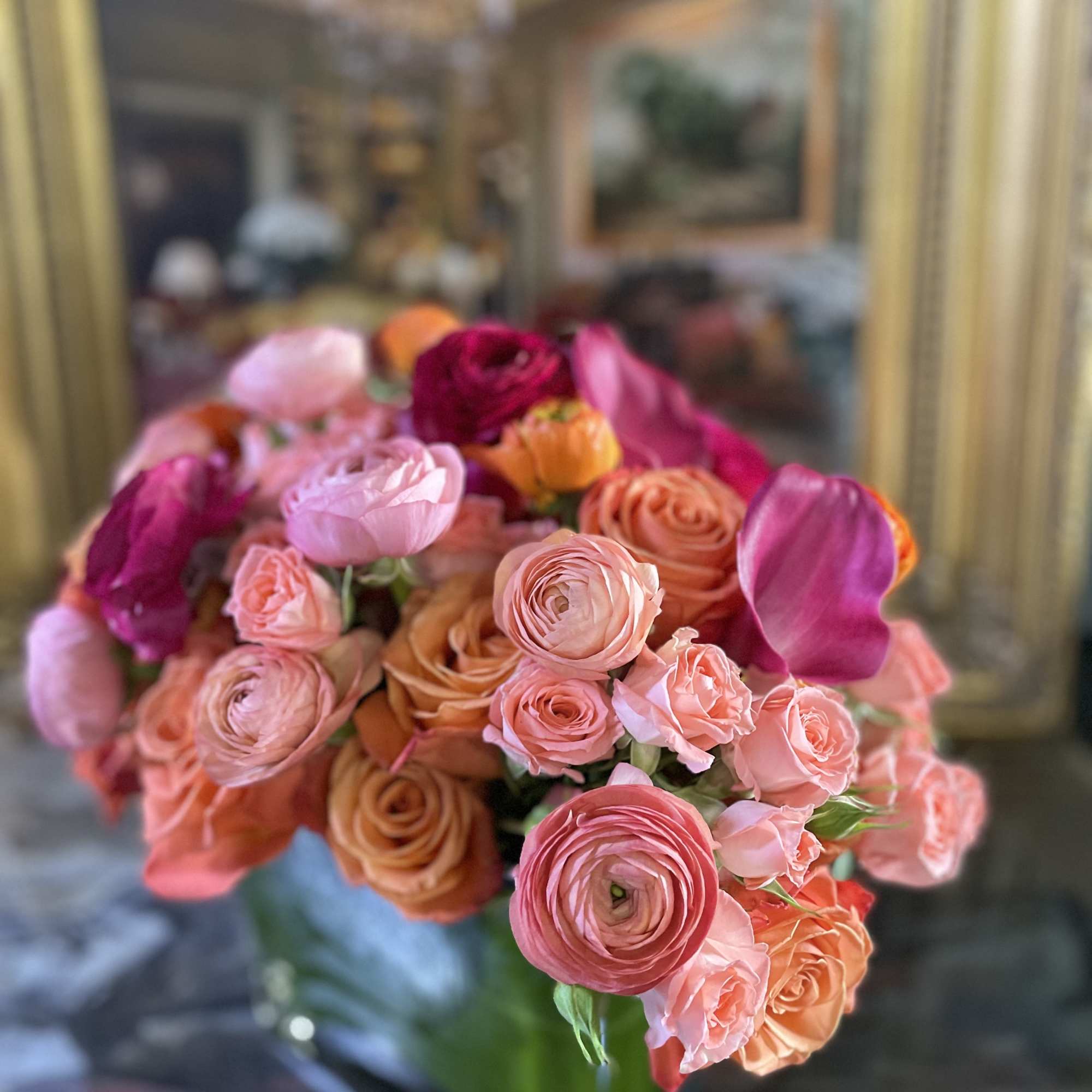 Bouquet of pink and peach roses with magenta blooms in a glass vase