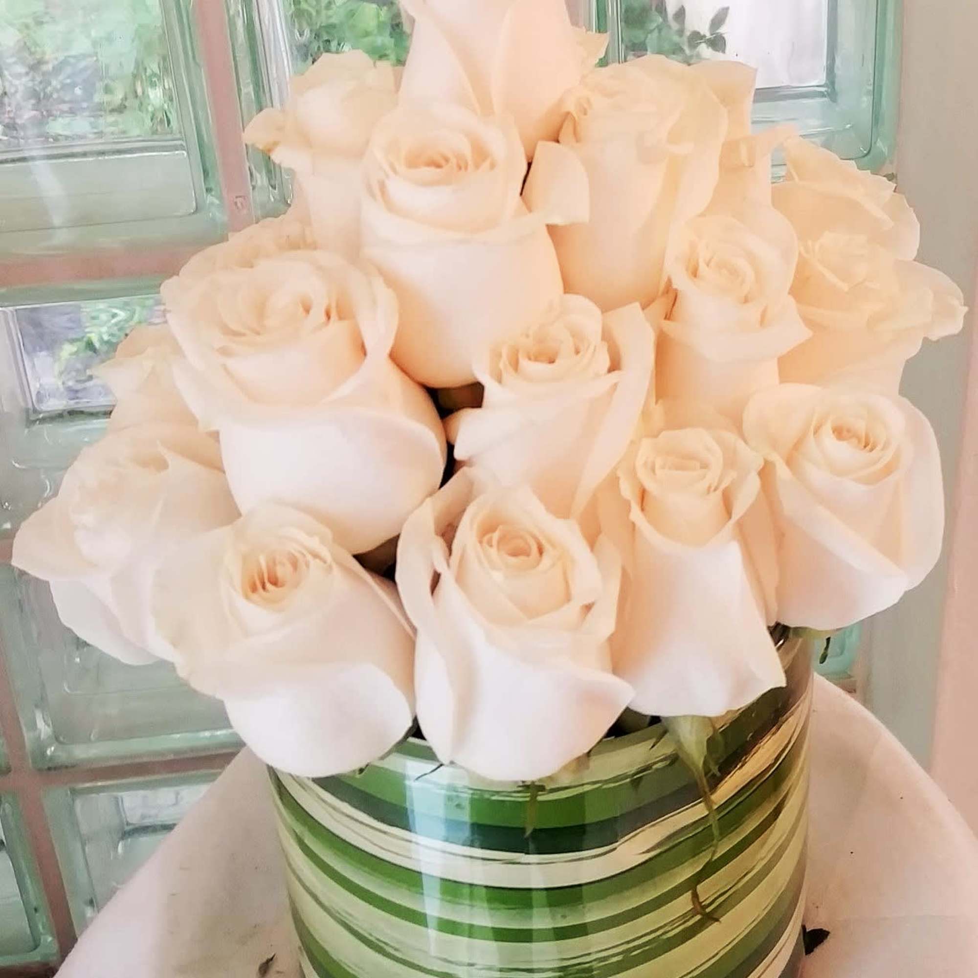 Bouquet of pale cream roses in a striped green vase