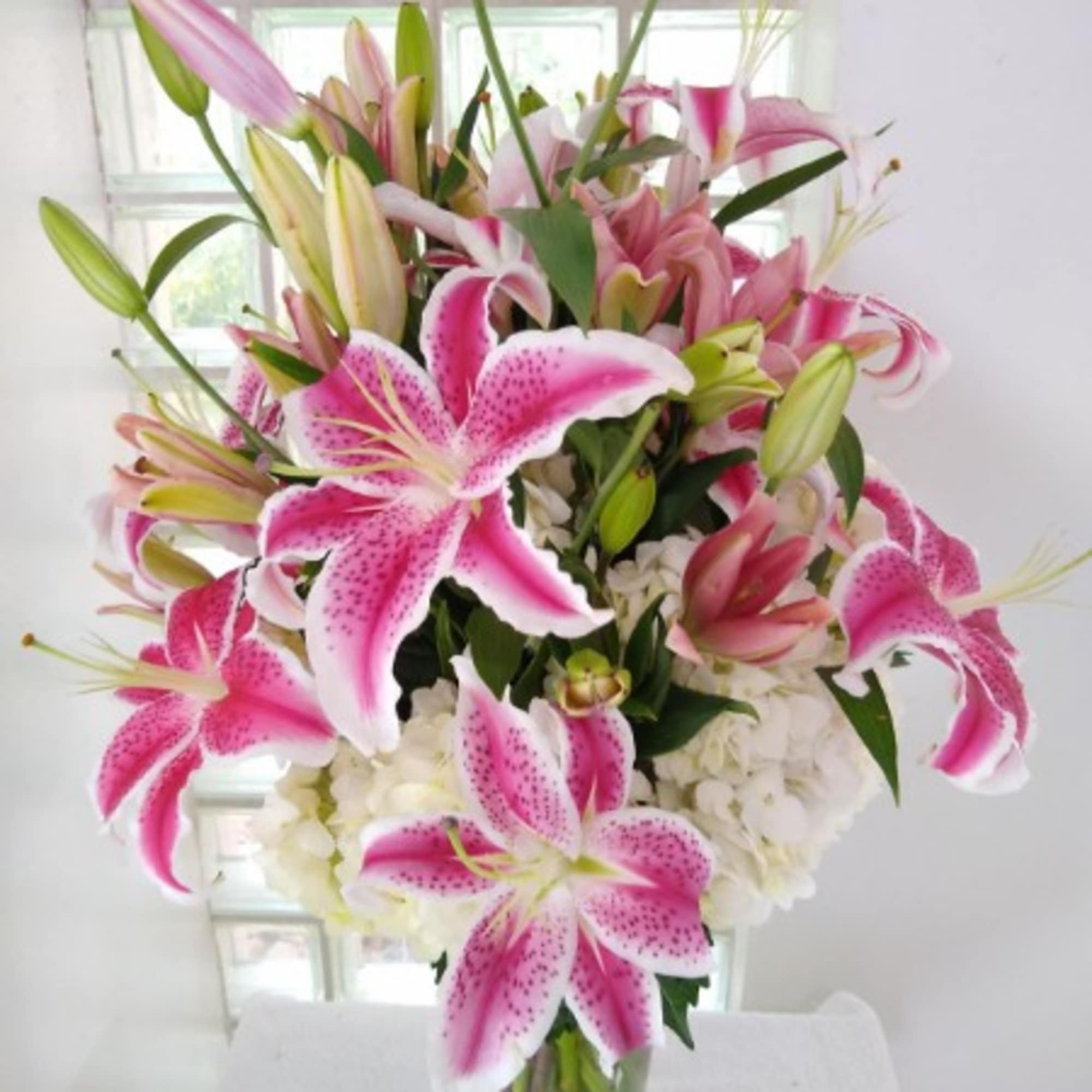 Pink and white lilies arranged in a clear glass vase