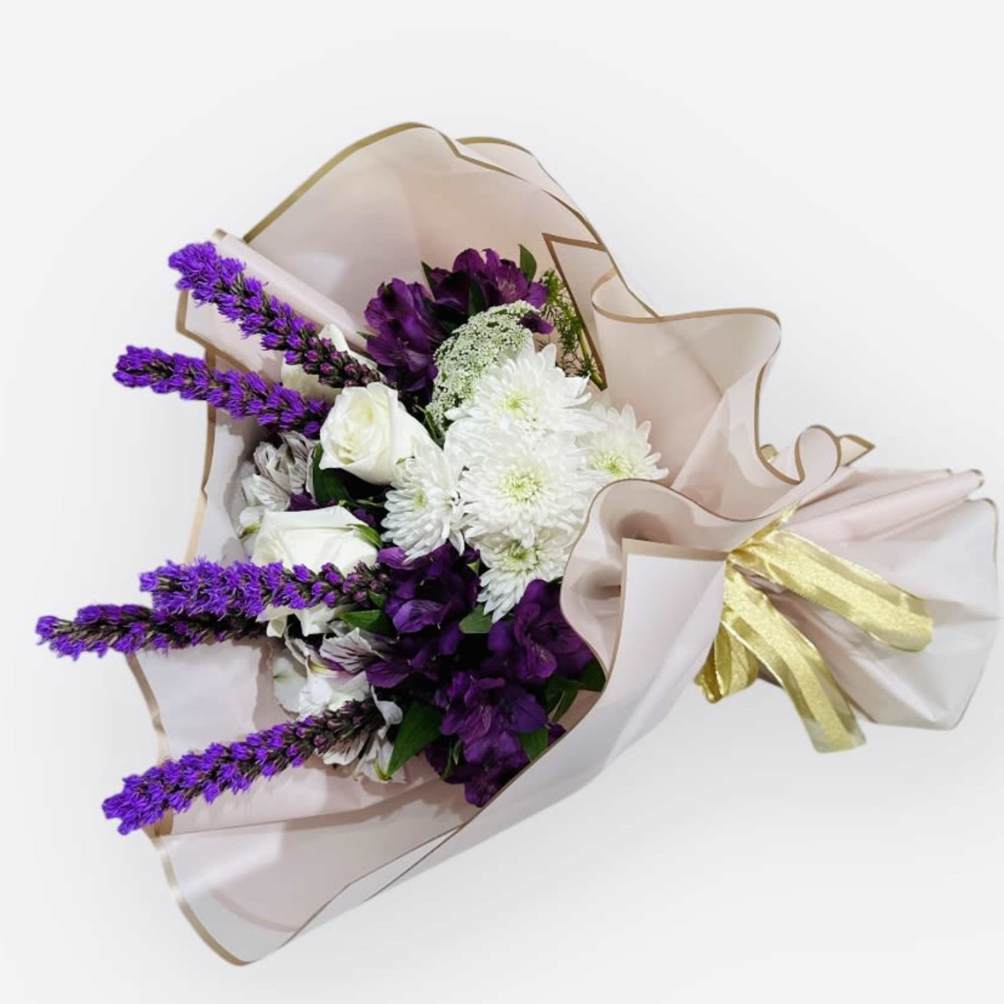 Bouquet of purple and white flowers wrapped in beige paper with a gold ribbon