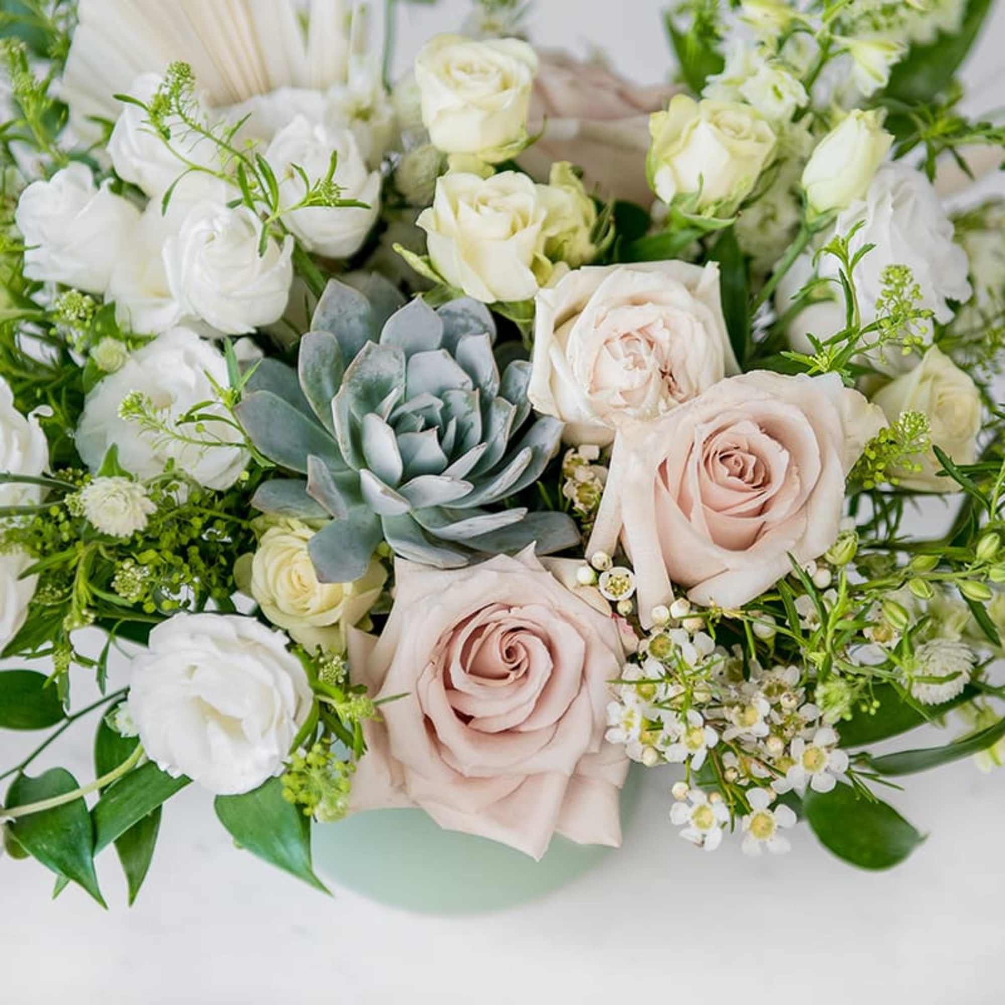 Bouquet of pale roses and white blooms with a blue-green succulent
