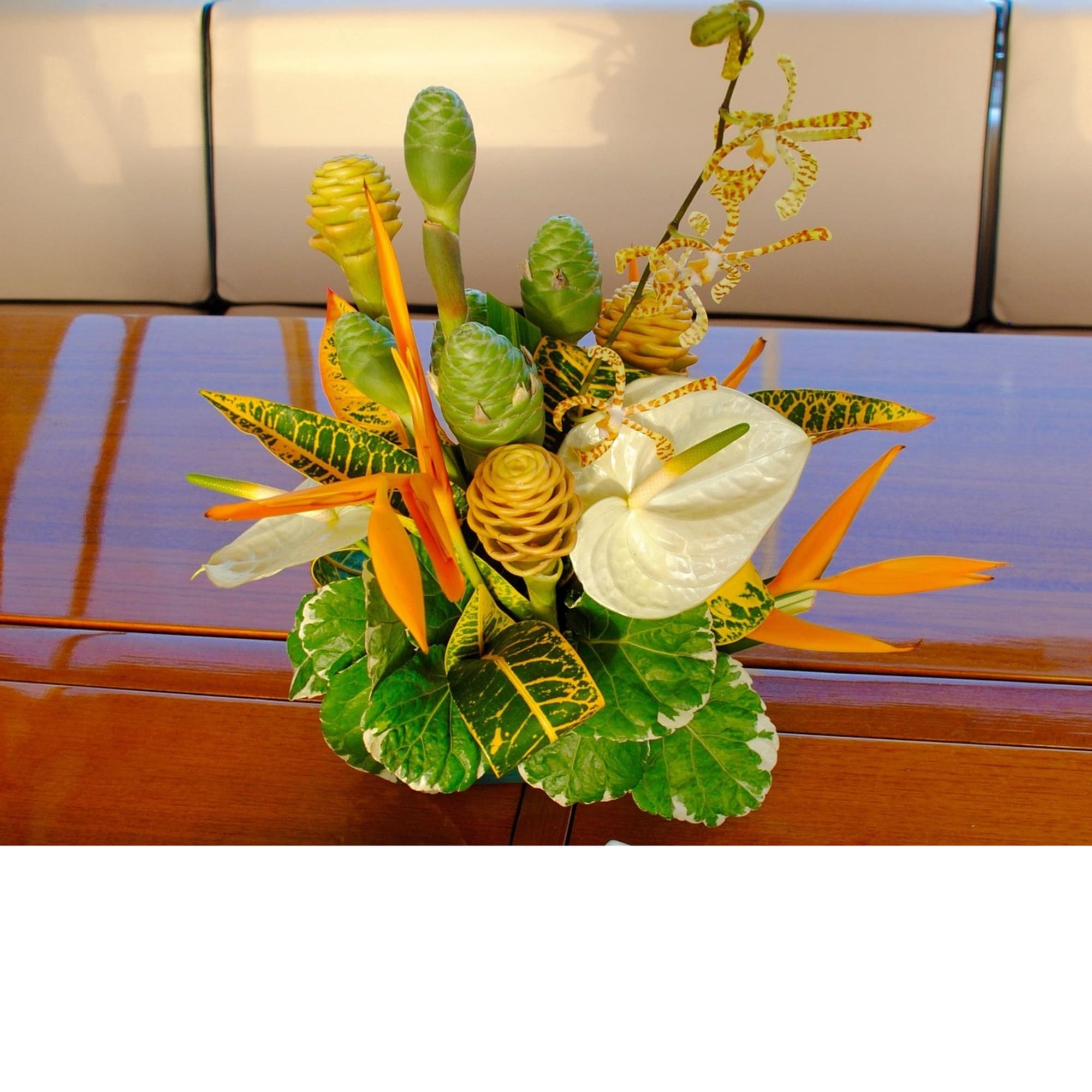 Tropical arrangement with orange blooms, white anthuriums, and green cones in a compact upright design