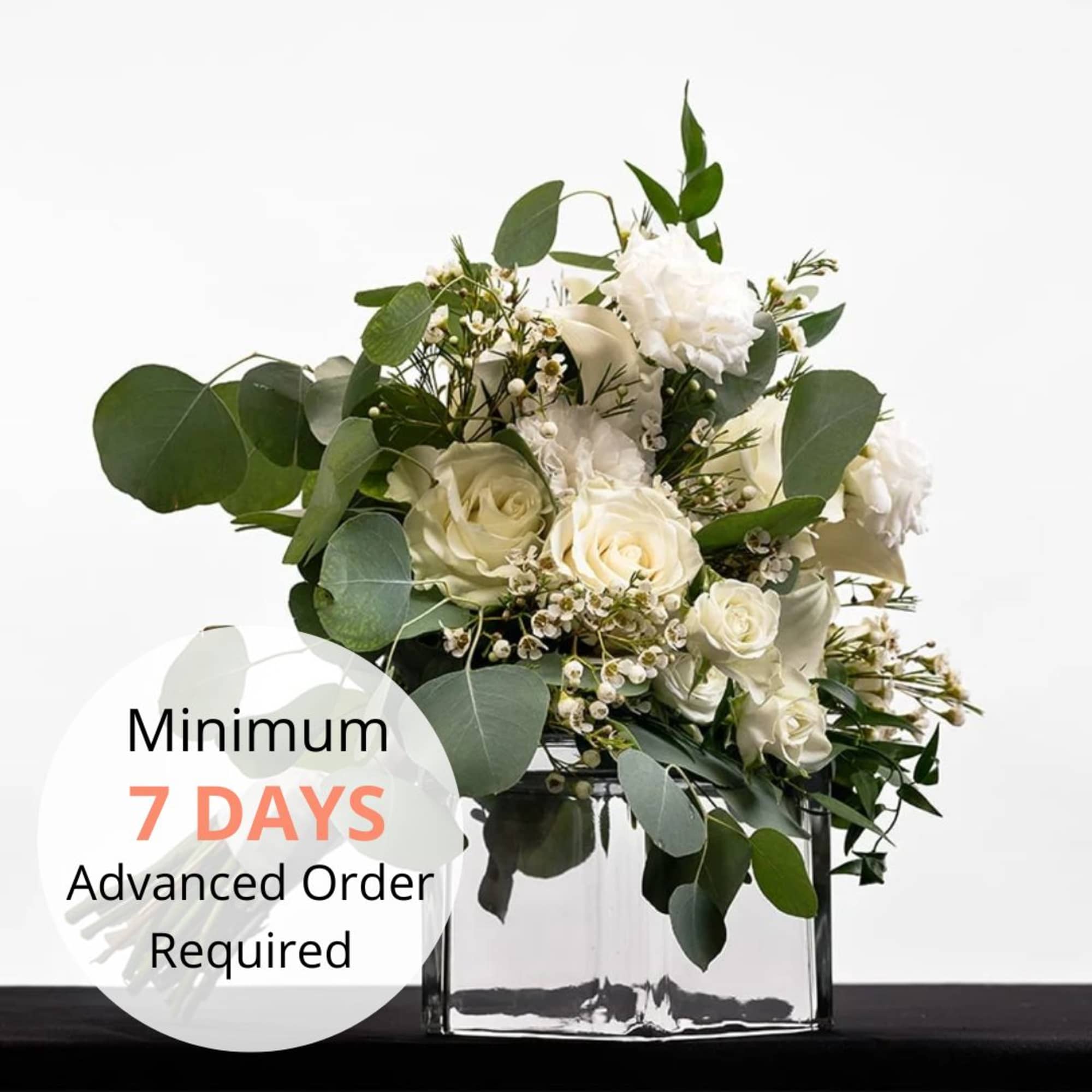 White rose and carnation arrangement with eucalyptus in a clear glass cube vase