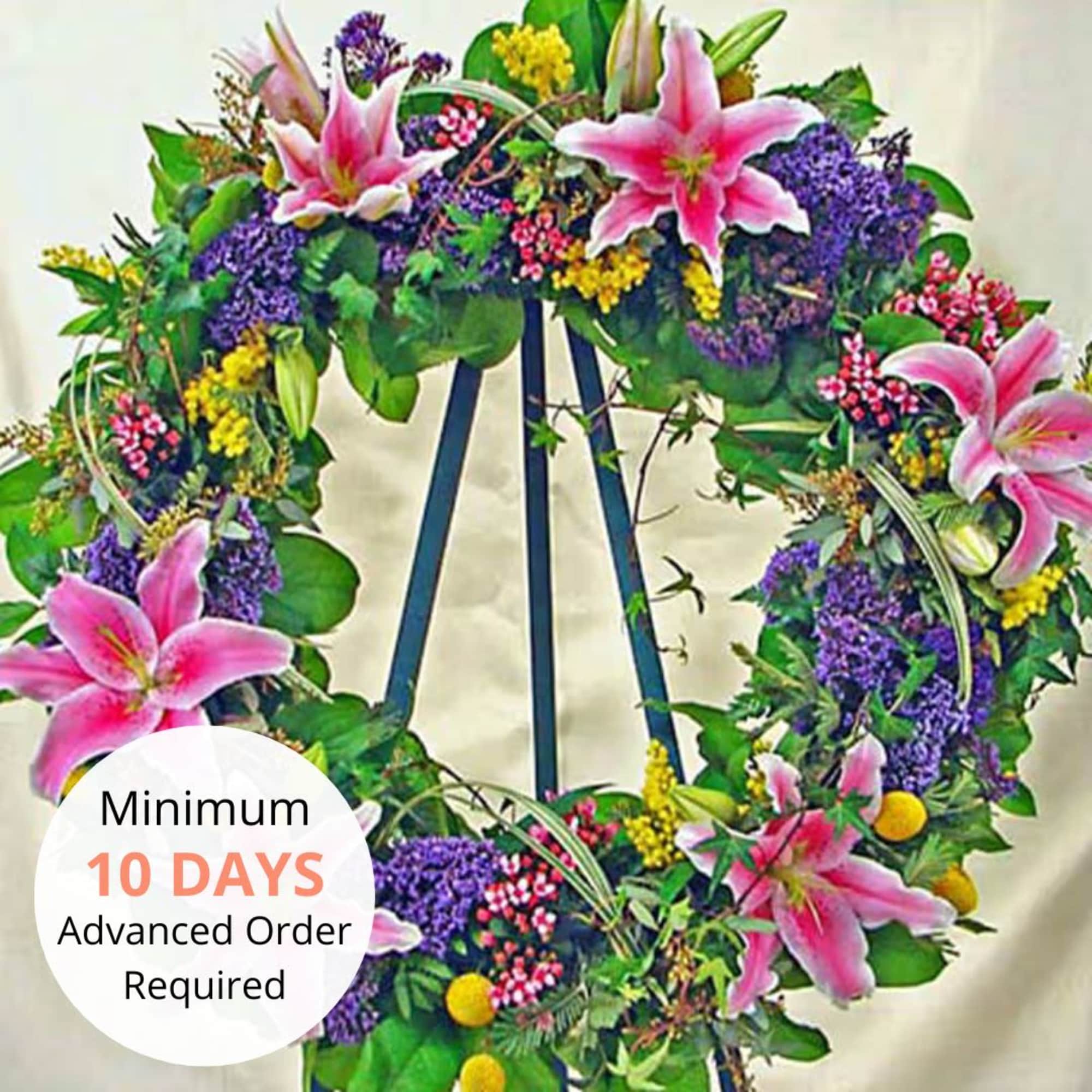 Standing wreath of pink lilies and mixed colorful flowers on a metal easel.