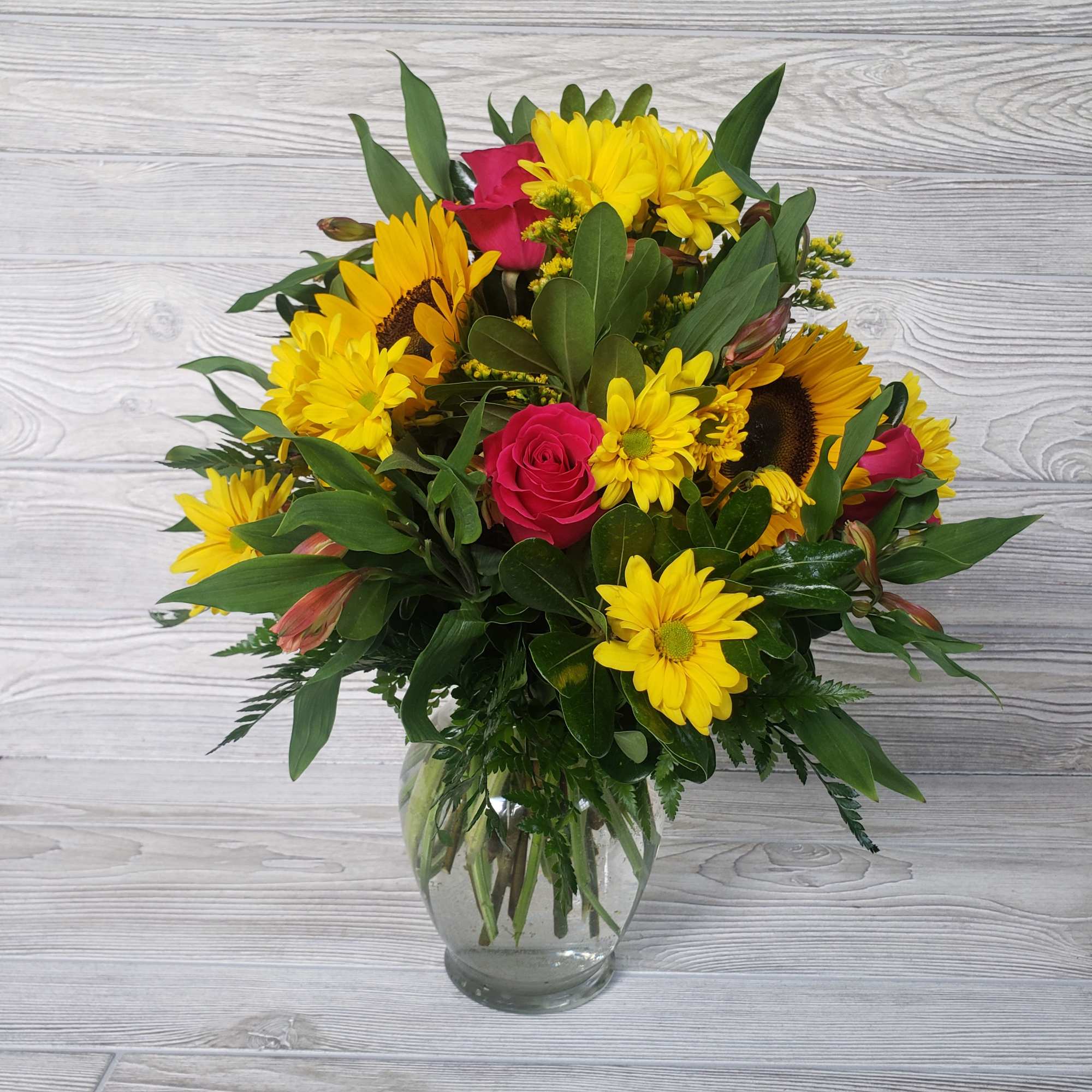 Yellow daisies and pink roses in a clear glass vase