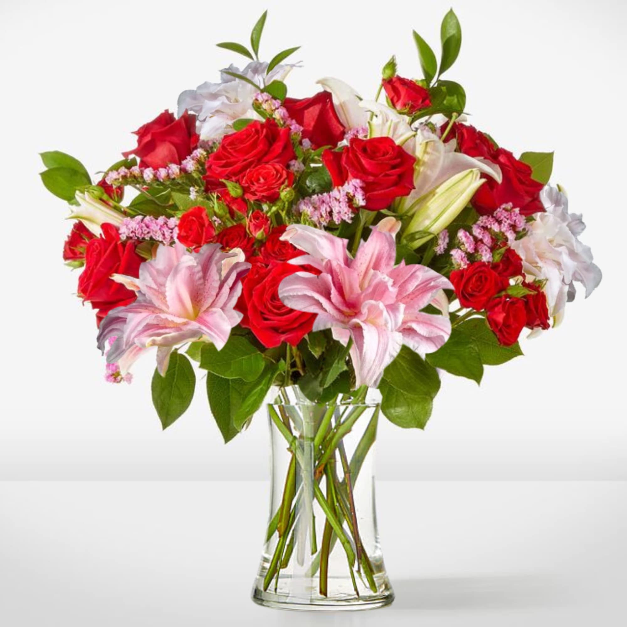 Bouquet of red and pink roses with lilies in a clear glass vase