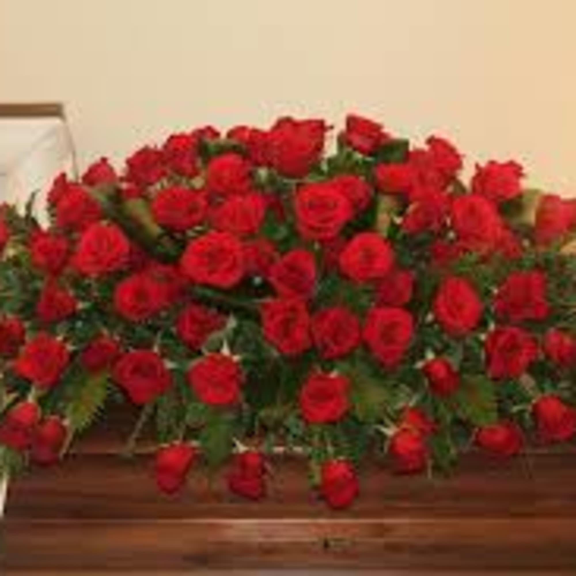 Large casket spray of red roses on a wooden casket