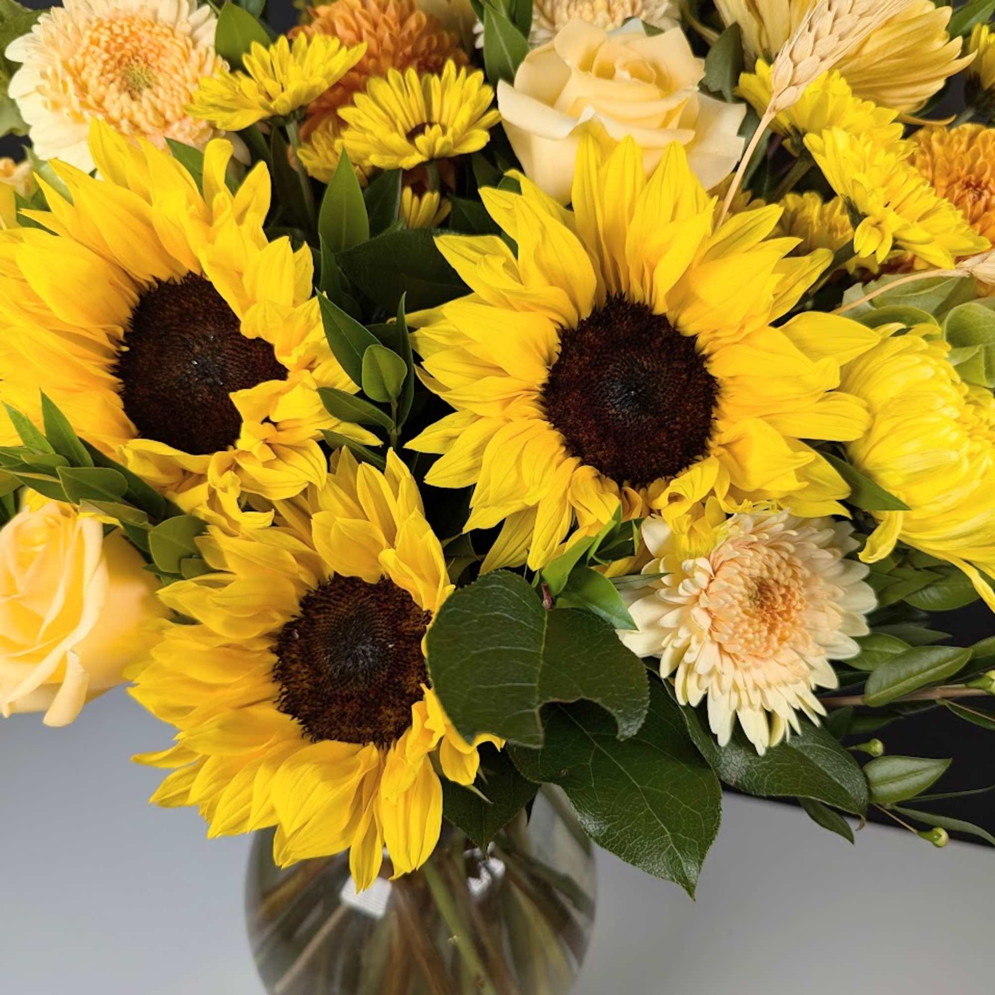Yellow sunflower and rose bouquet in a glass vase