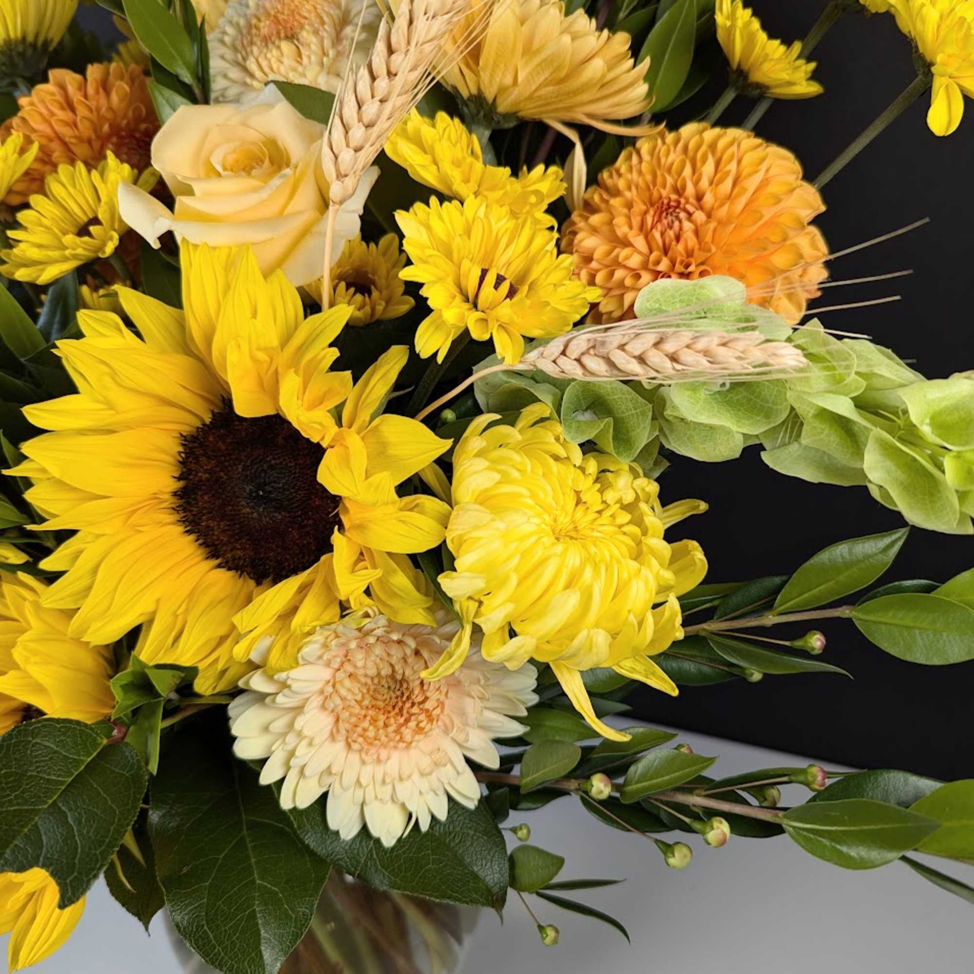 Yellow sunflower and chrysanthemum bouquet in a glass vase