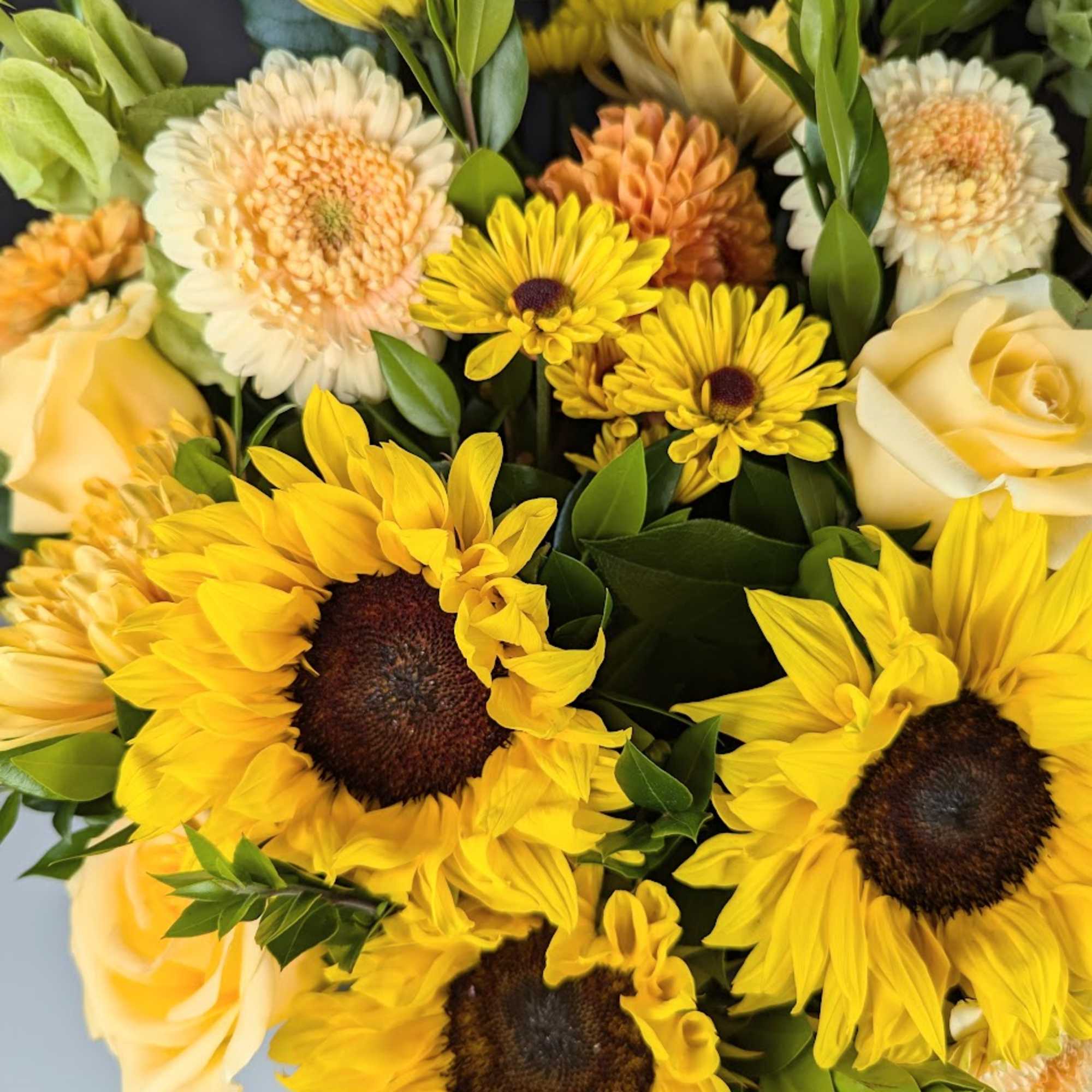 Bouquet of yellow sunflowers and pale cream roses with mixed blooms