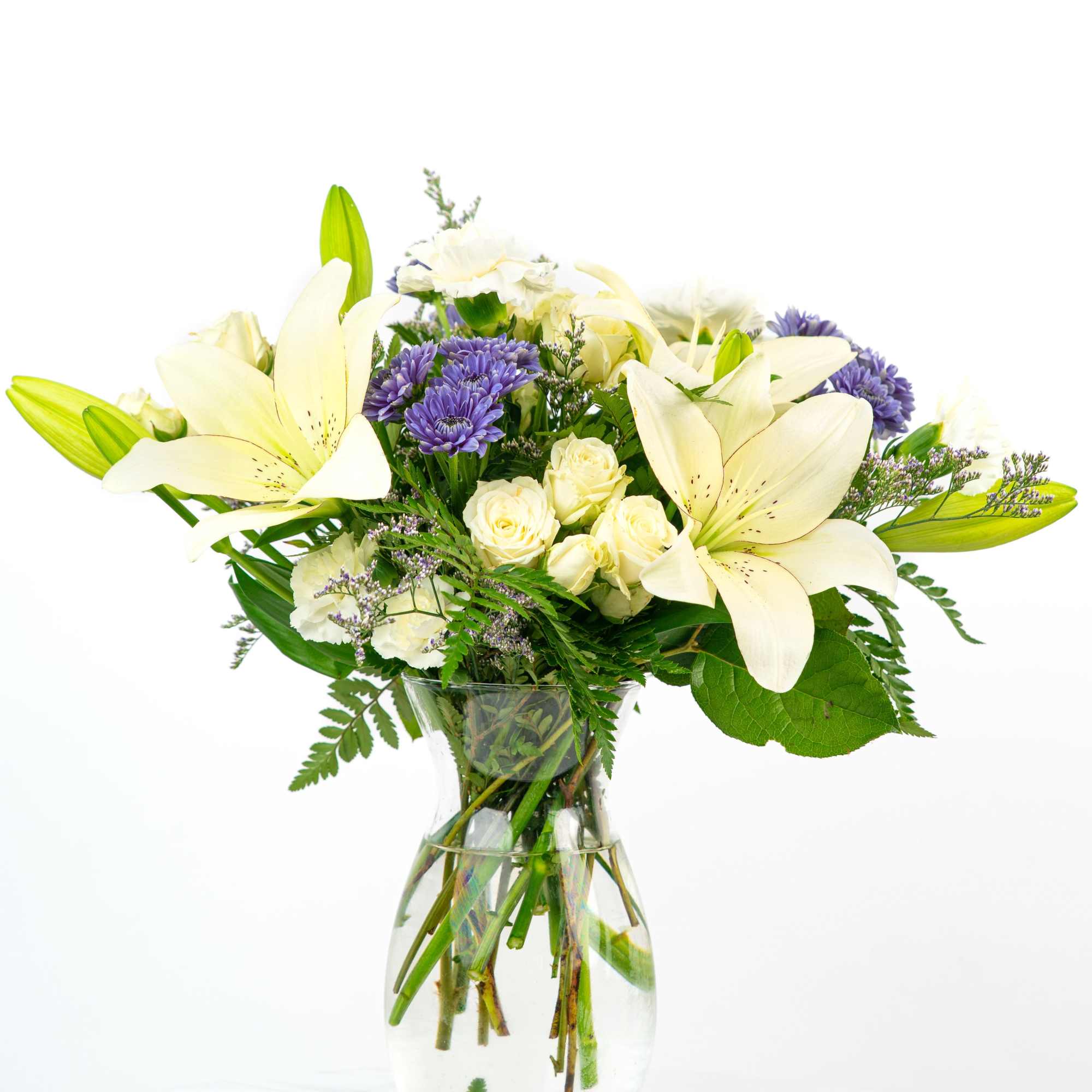 White lilies and purple flowers in a clear glass vase
