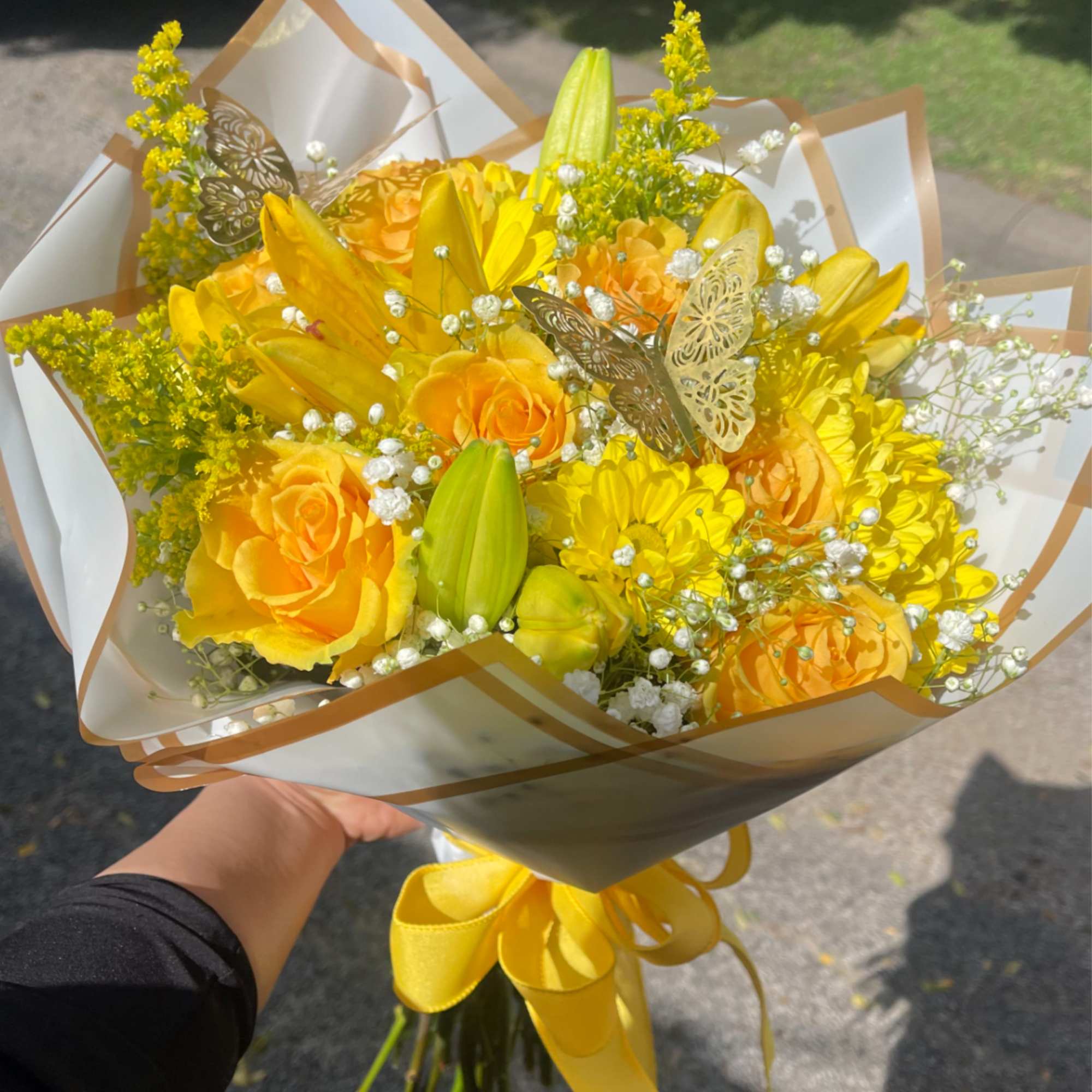 Yellow roses, lillie's, daisies, baby's breath, and  Solidago wrapped in white