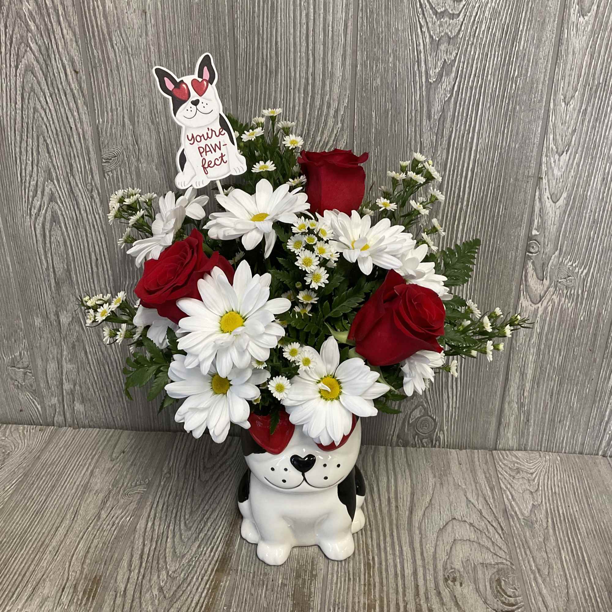 Red roses and white daisies in a dog-shaped planter with a paw-fect sign
