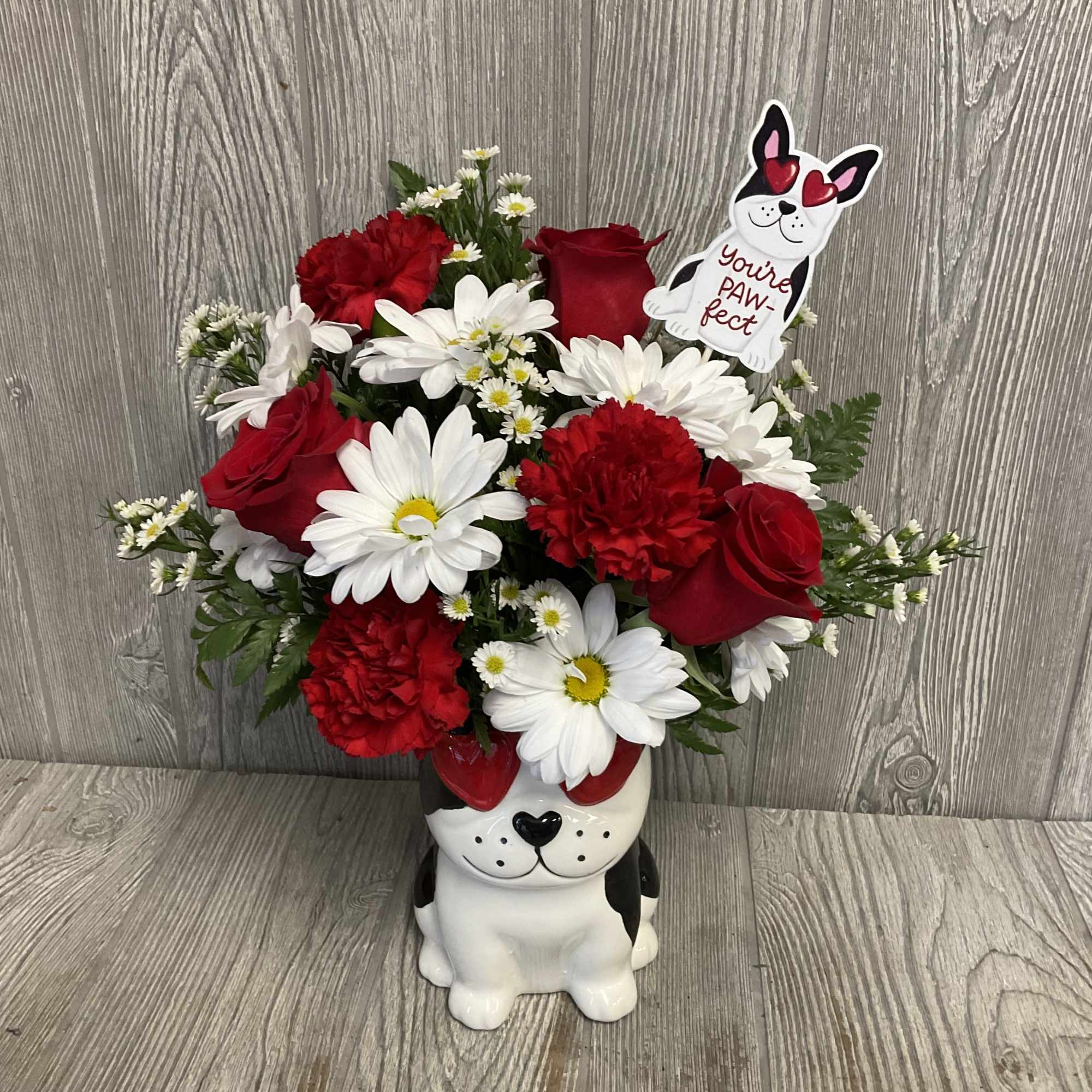 Red and white flower arrangement in a dog-shaped vase with a paw-print topper