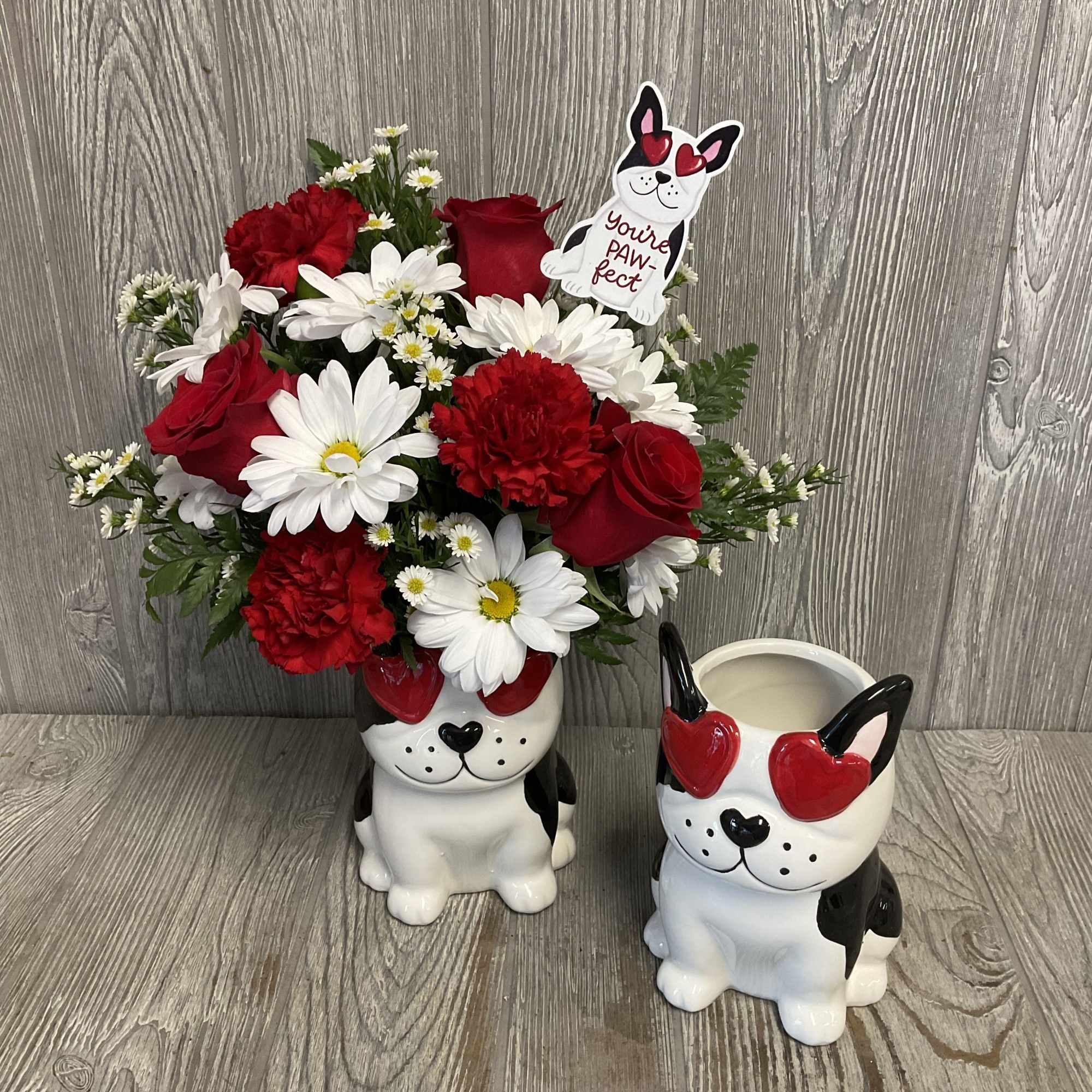 Red and white flower arrangement in a dog-shaped vase with a matching mug