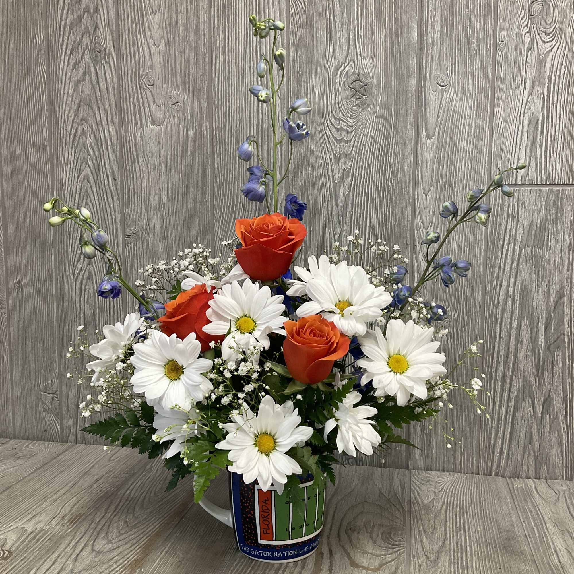 Orange roses and white daisies in a Florida mug vase