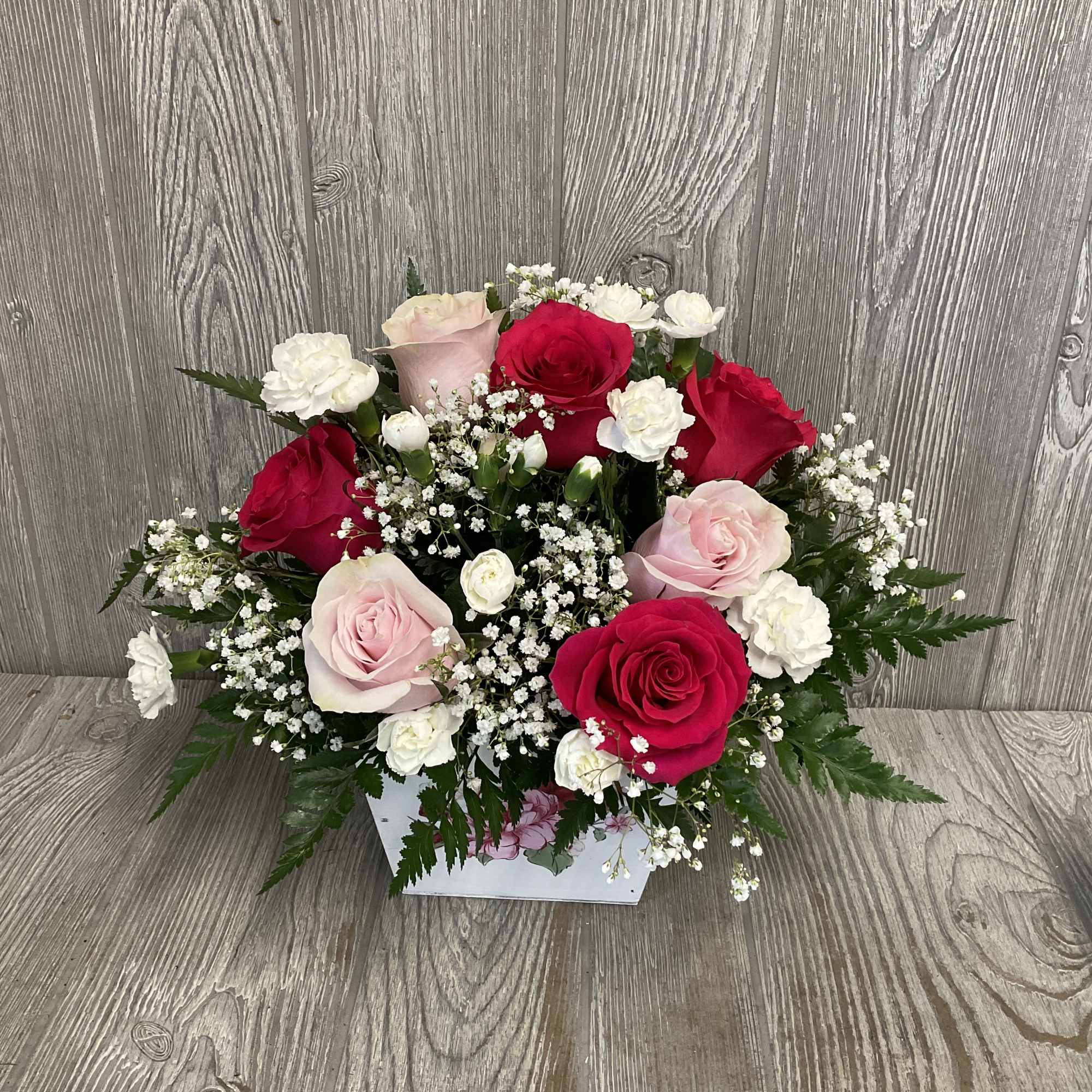Pink and red roses with white filler flowers in a white box