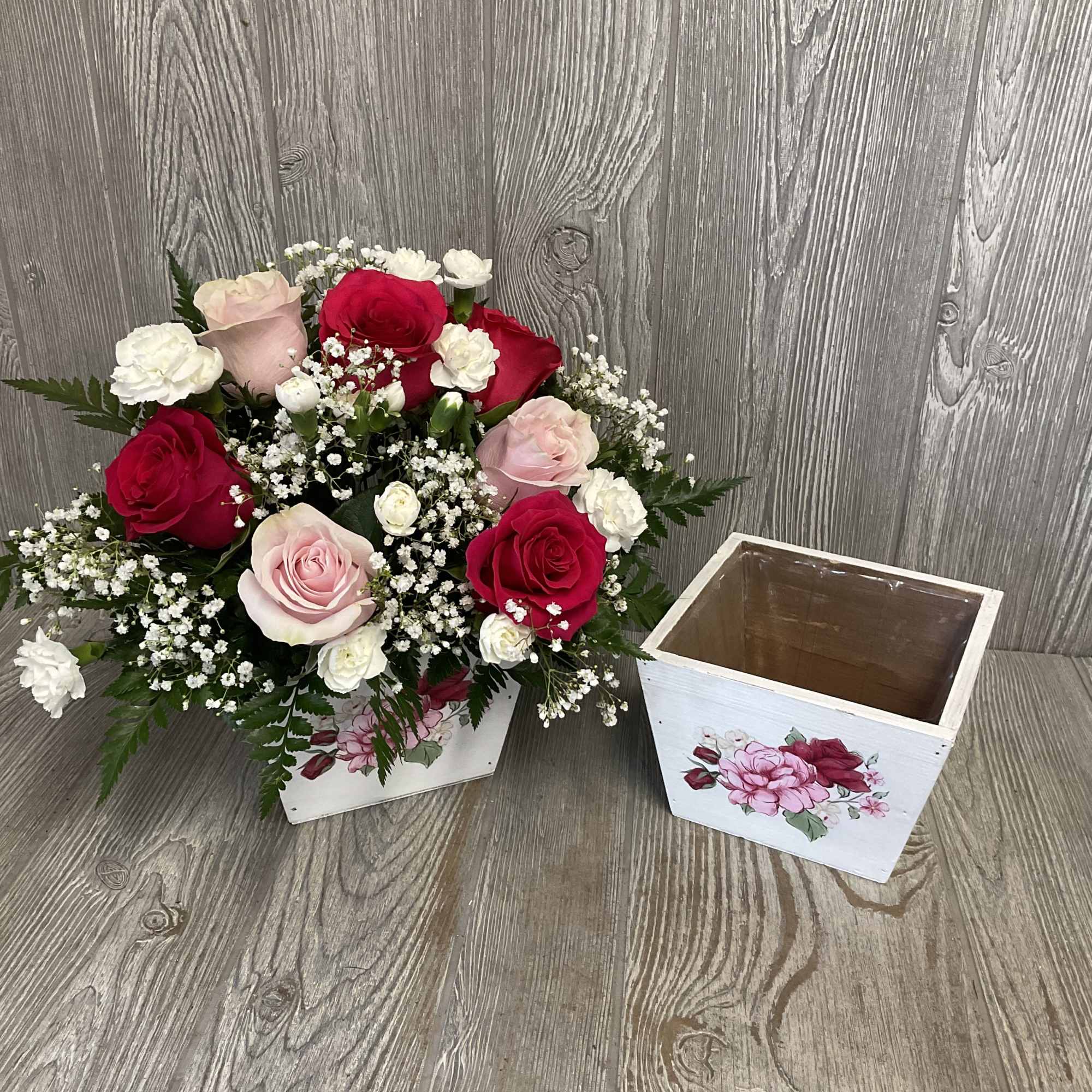 Bouquet of red and pink roses with baby's breath beside a white wooden box
