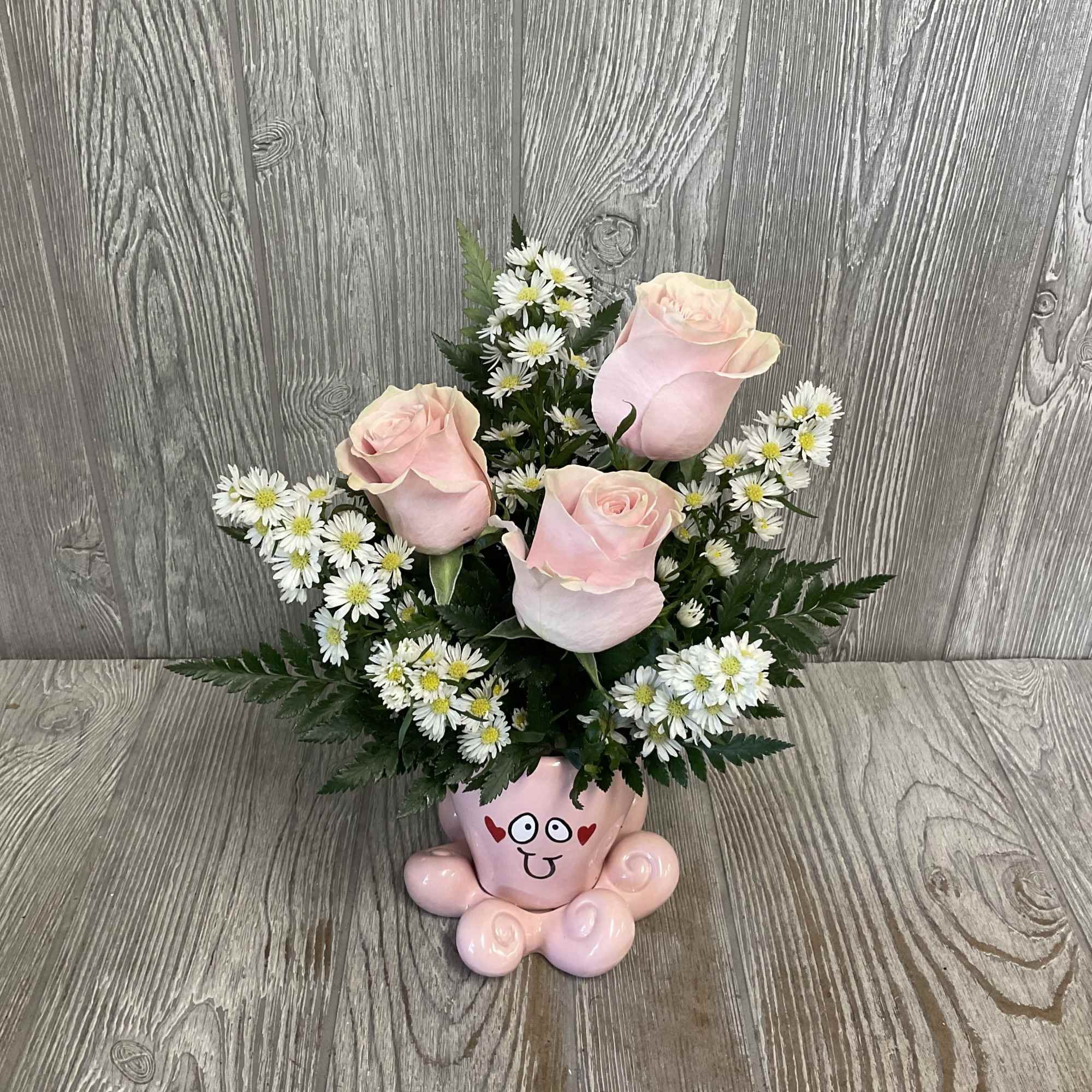 Pink roses and white daisies arranged in a pink cartoon vase