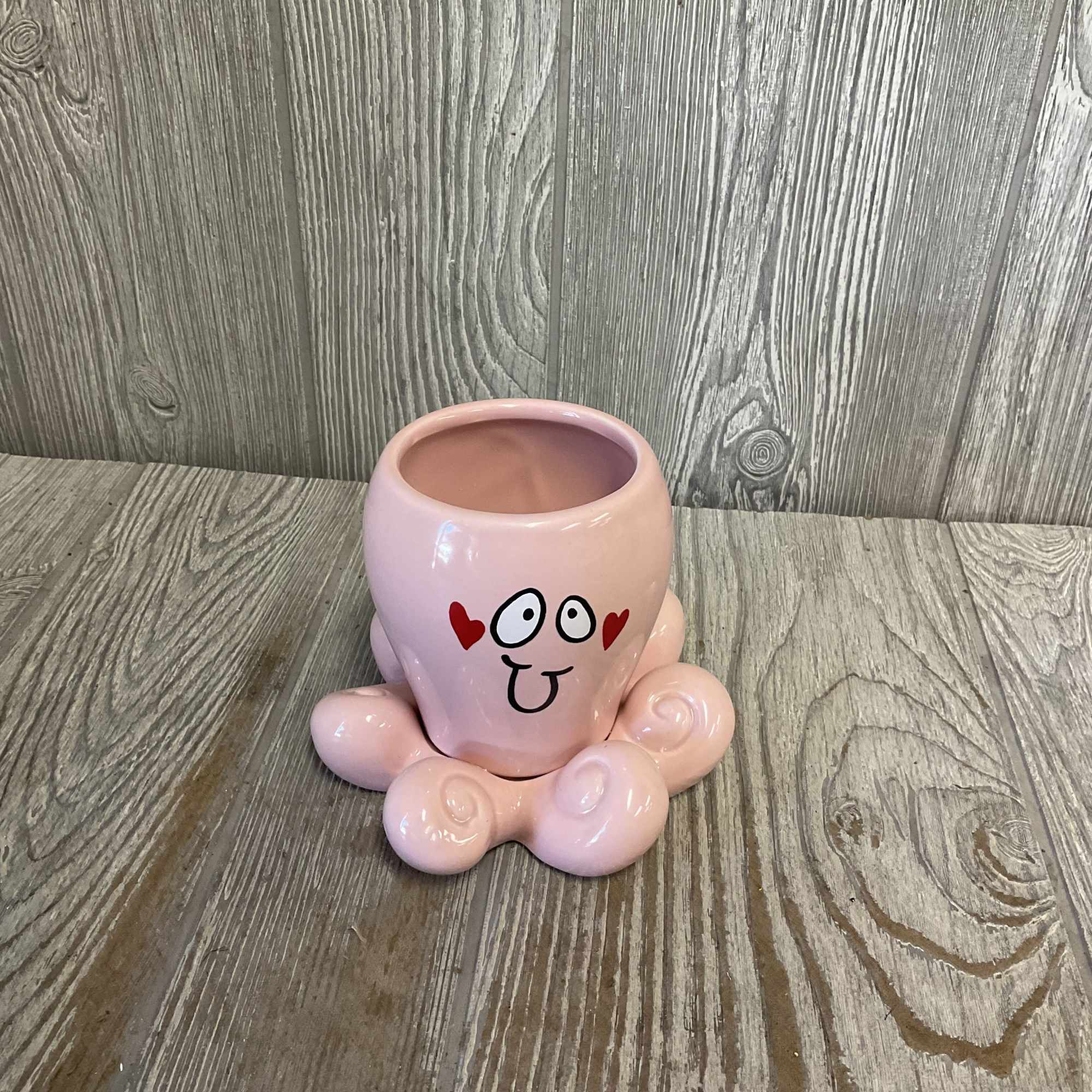 Pink ceramic planter with a cartoon face and heart accents