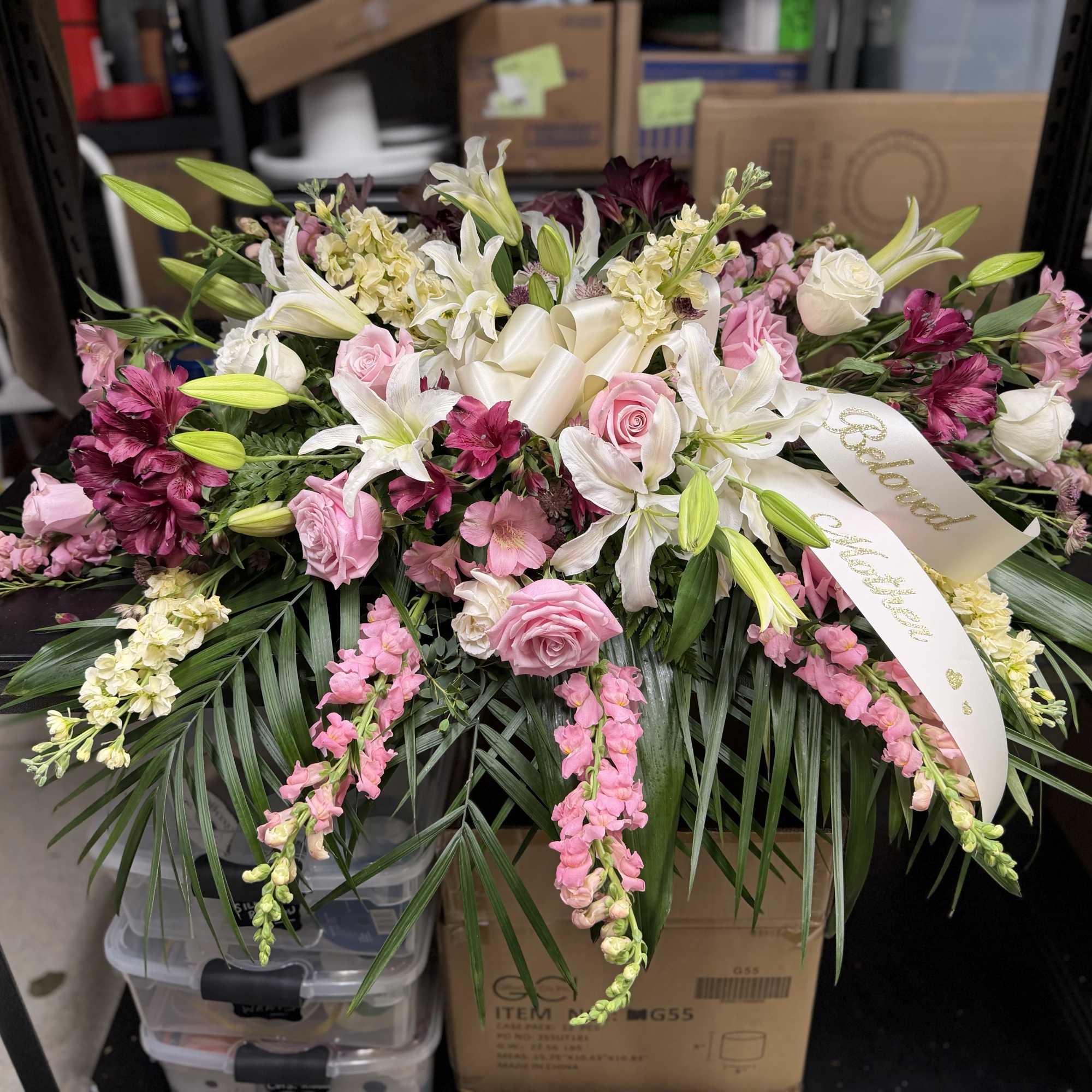Pink and white floral spray with lilies and roses, accented by a ribbon
