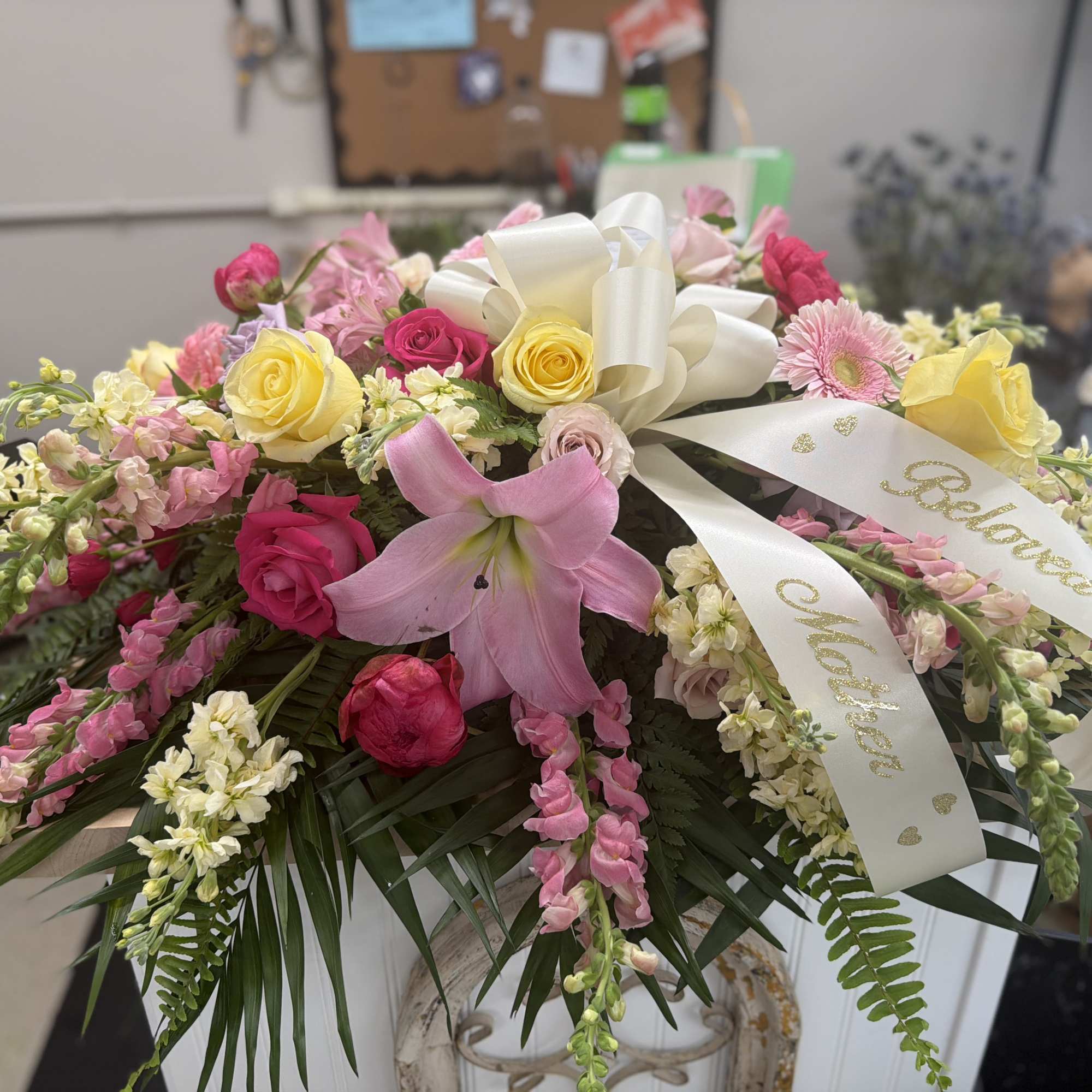 Pink and yellow rose arrangement with a pink lily and white ribbon
