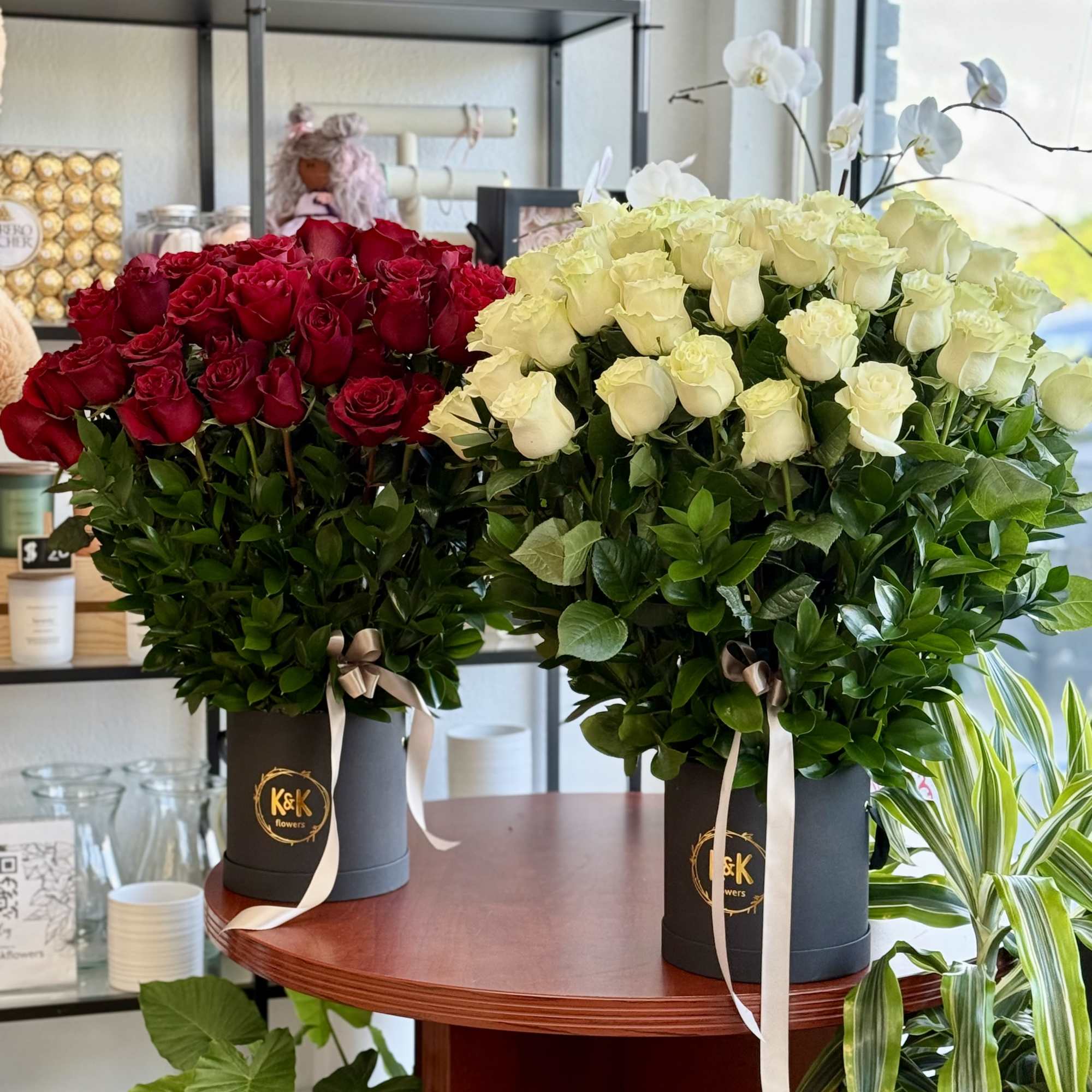 Two large rose arrangements in black boxes, one red and one white