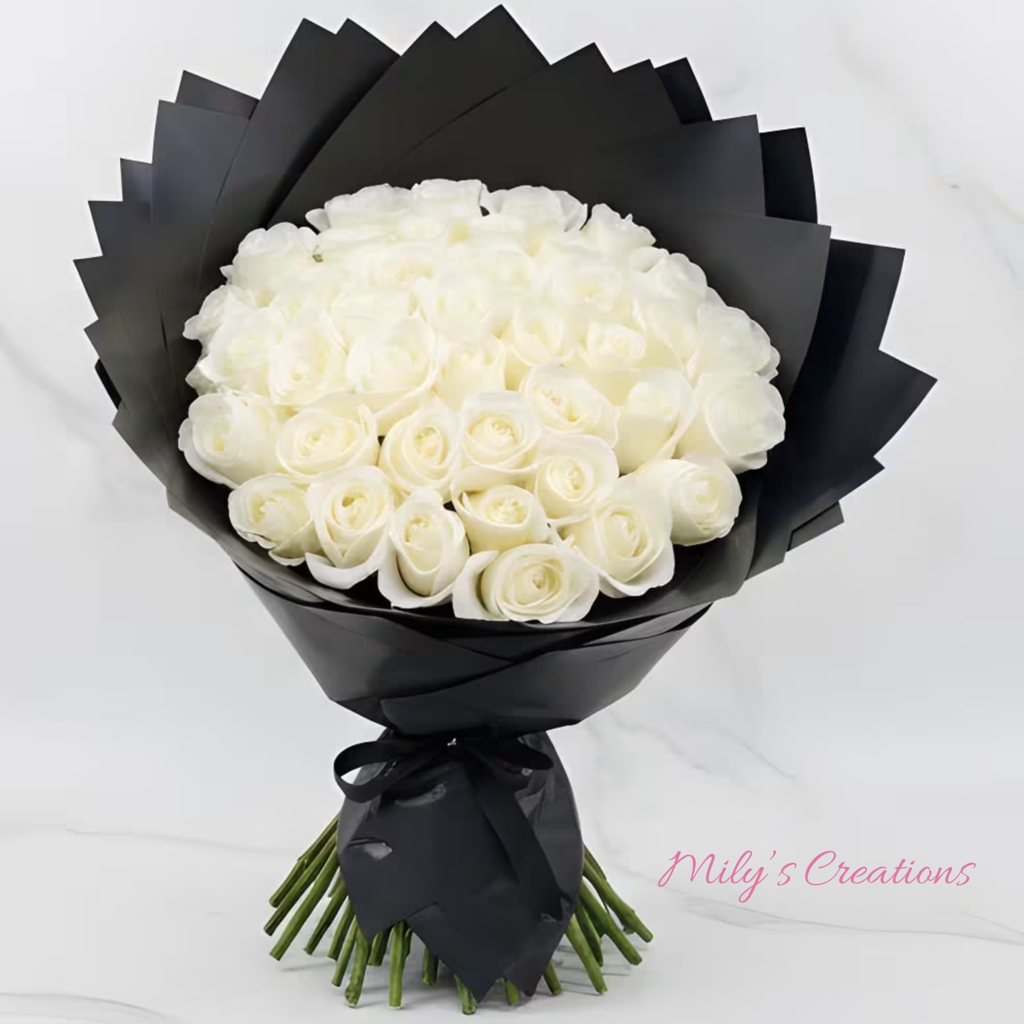 Large bouquet of white roses wrapped in layered black paper and tied with a black ribbon