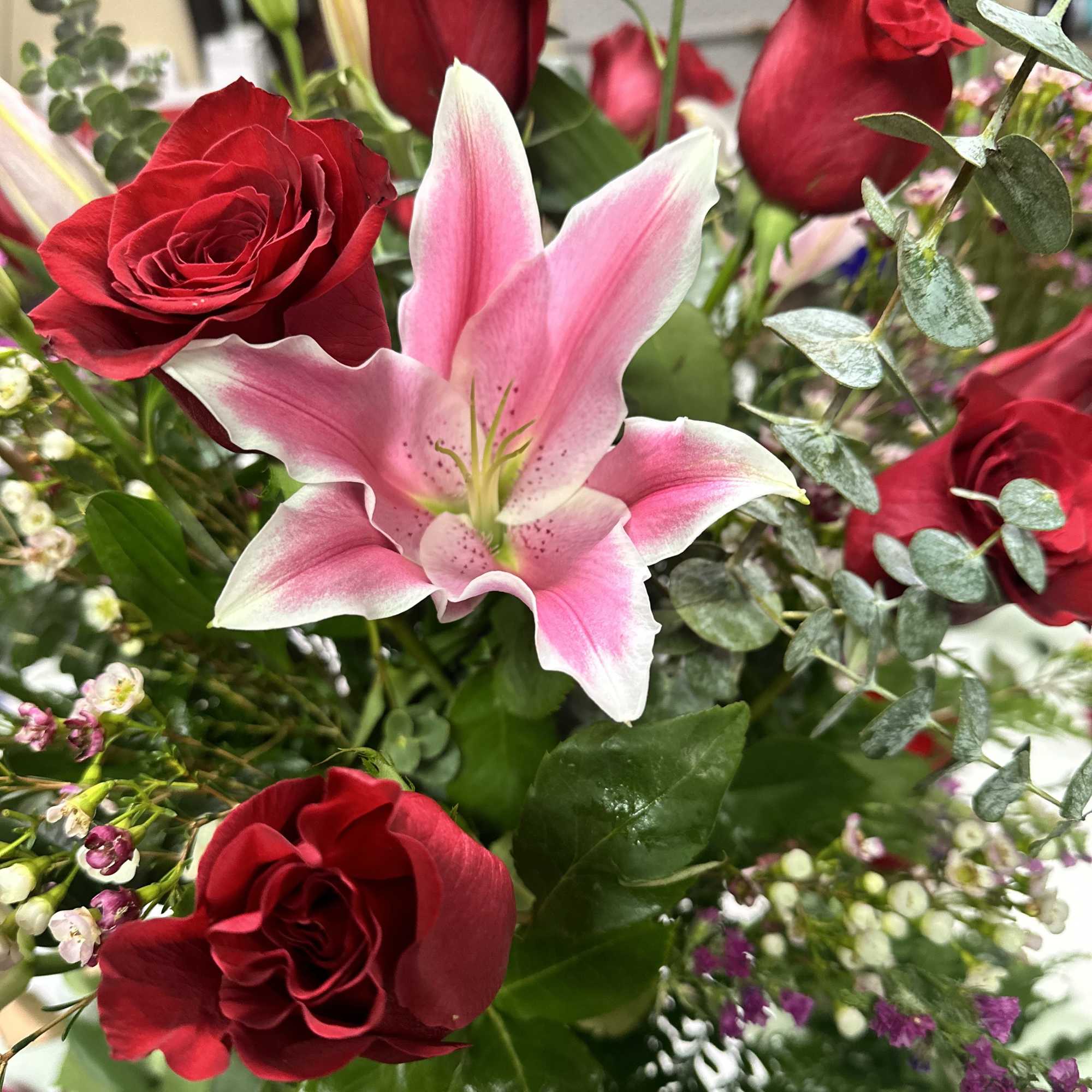 Red roses with a pink lily in a mixed bouquet