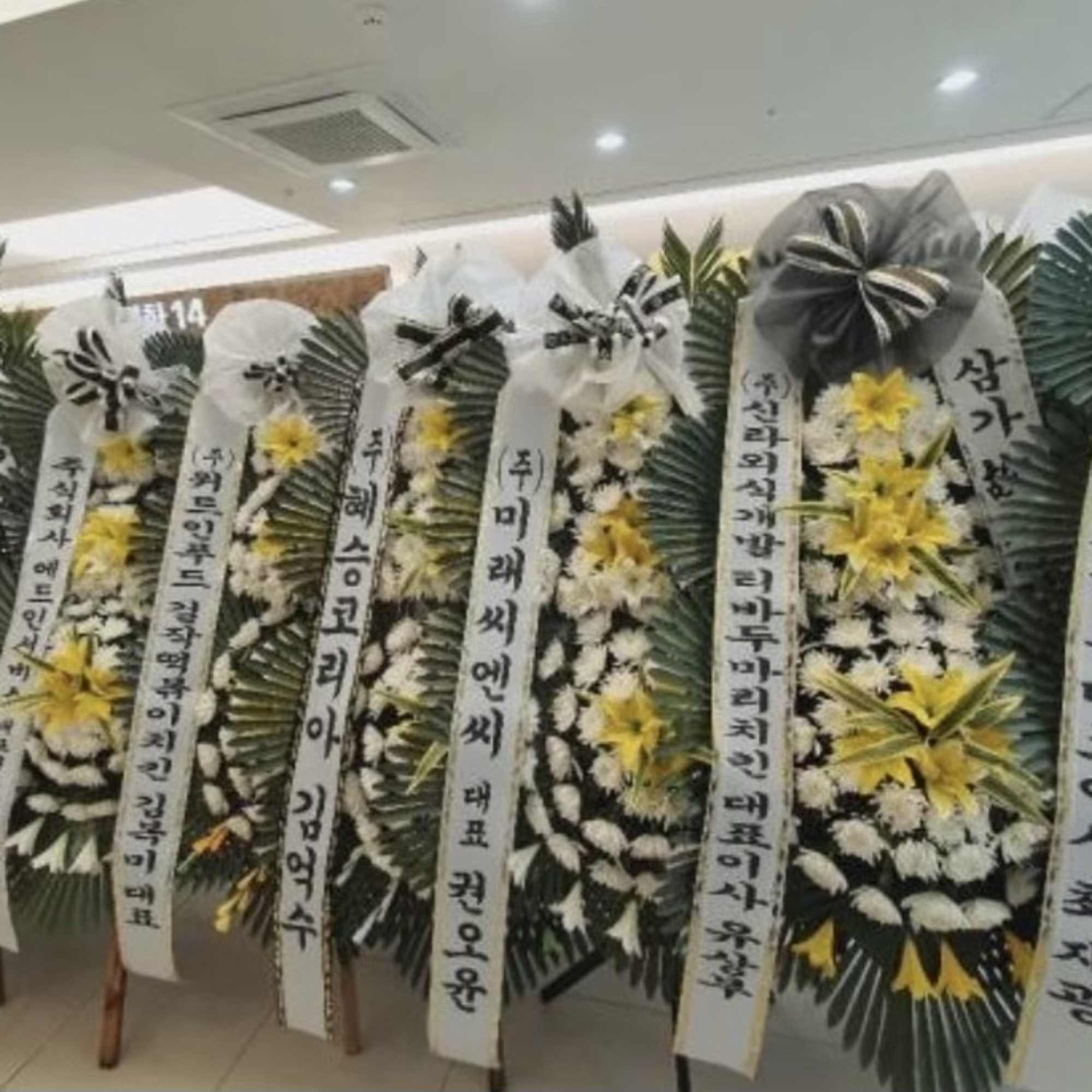 Standing funeral wreaths with white and yellow flowers and Korean condolence ribbons