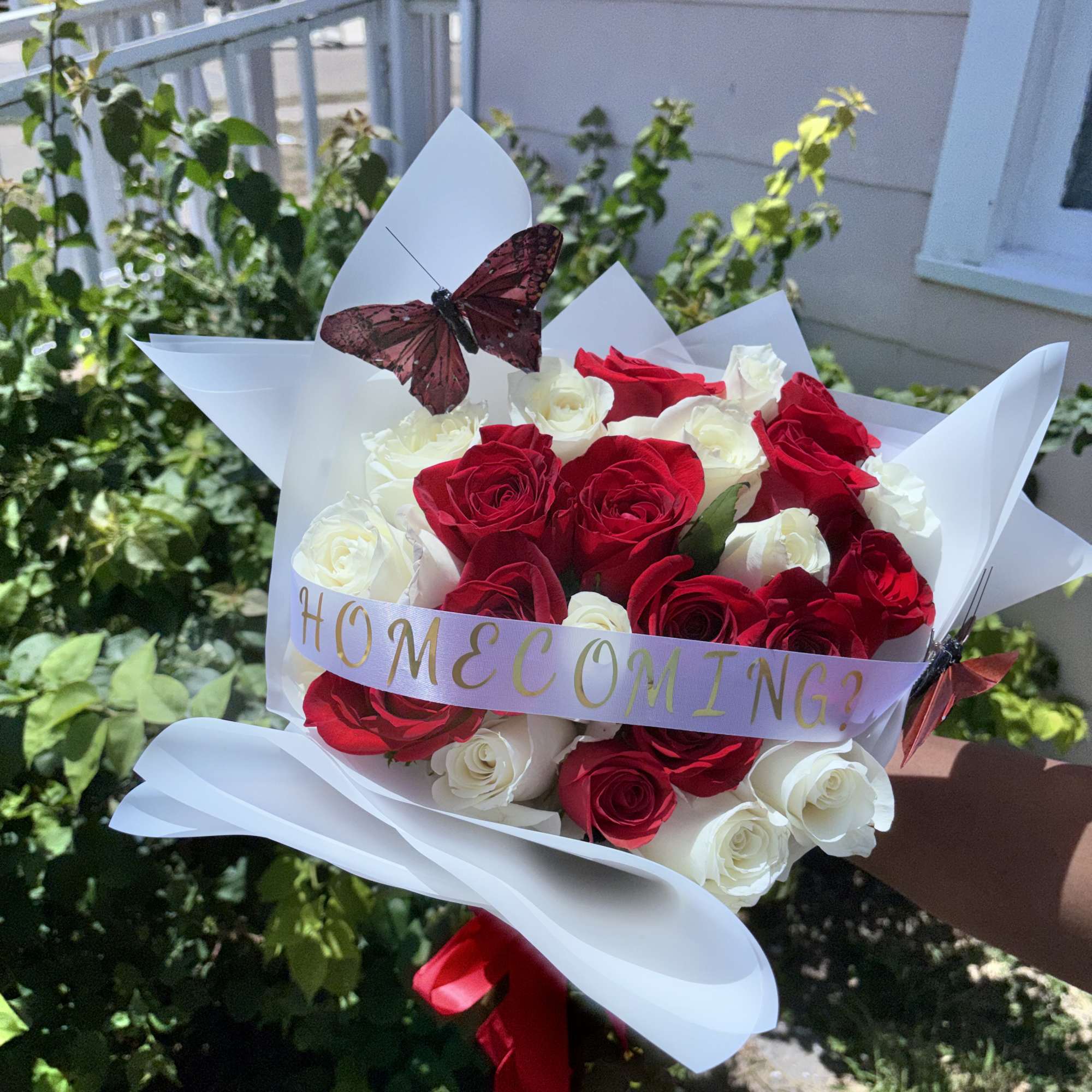 Bouquet of red and white roses wrapped in white paper with a butterfly decoration